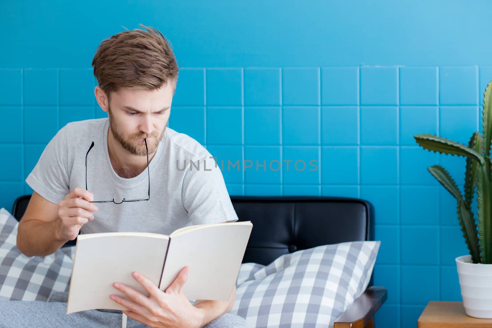 Young man reading book on sofa in the living room.