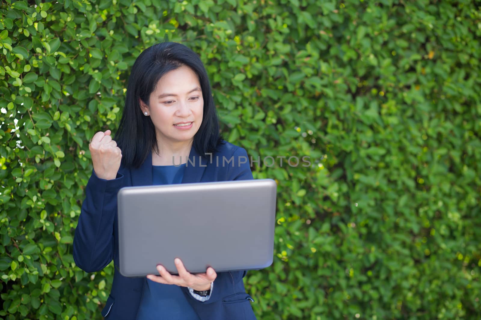 businesswoman holding computer notebook and showing thumb up making the ok gesture.
