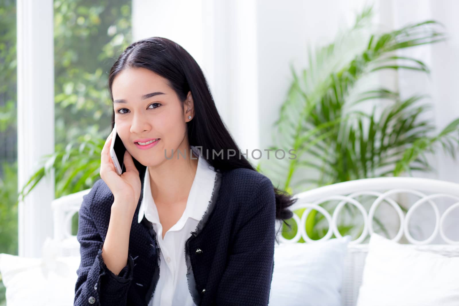 Portrait of woman sitting at sofa while talking a call at home - Business people.