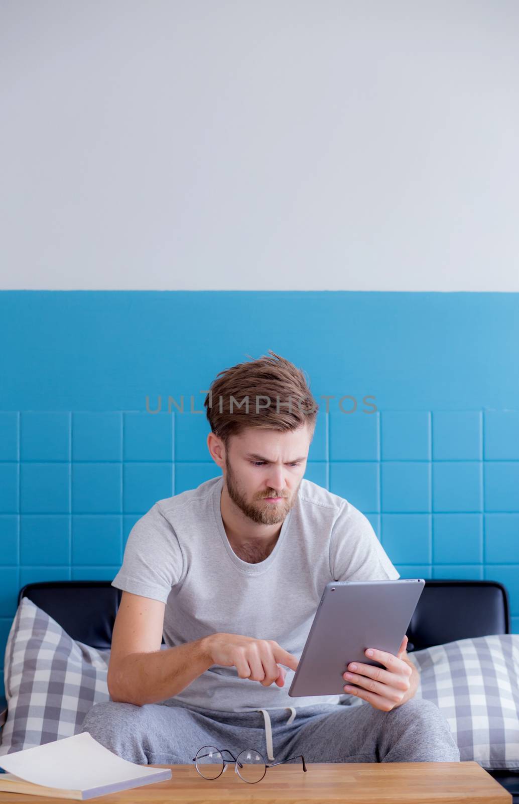 Happy man watching media content in a tablet sitting on a couch at home.