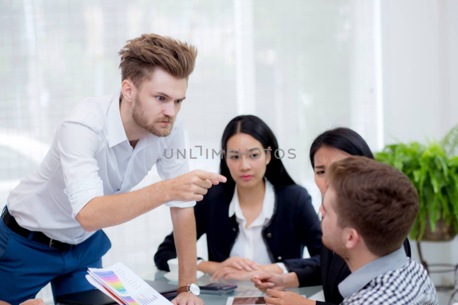 Group of businesspeople looking at businessman blaming his colleague in meeting