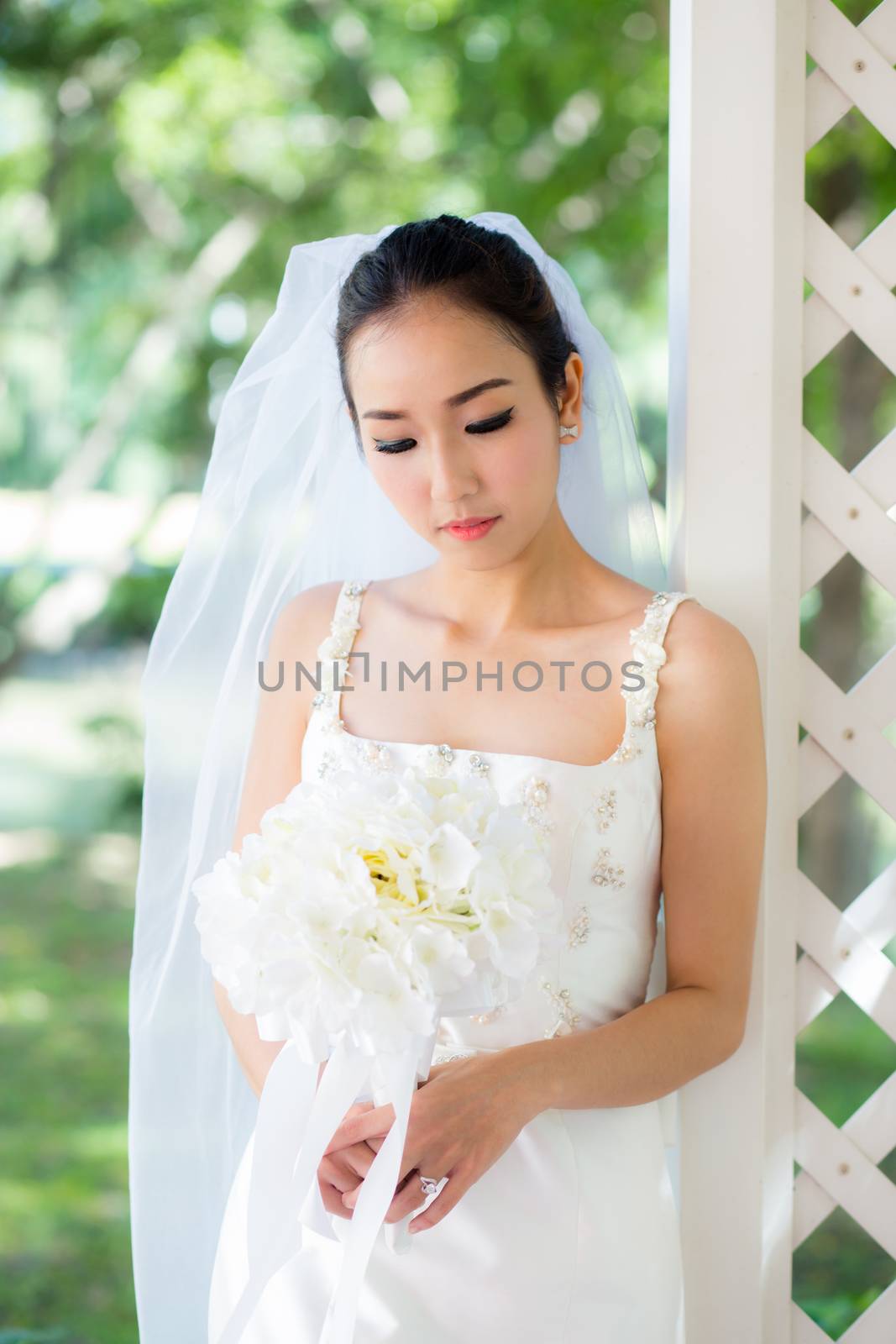 bride in a dress standing in a green garden and holding a weddin by nnudoo