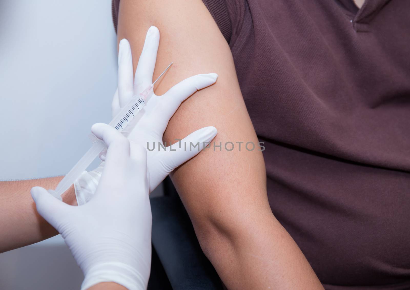 Close-up Of Doctor Injecting Patient With Syringe To Collect Blood