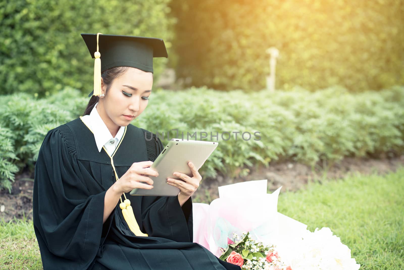 Graduate playing tablet in her hand feeling relaxing and so happiness in commencement day and search job new