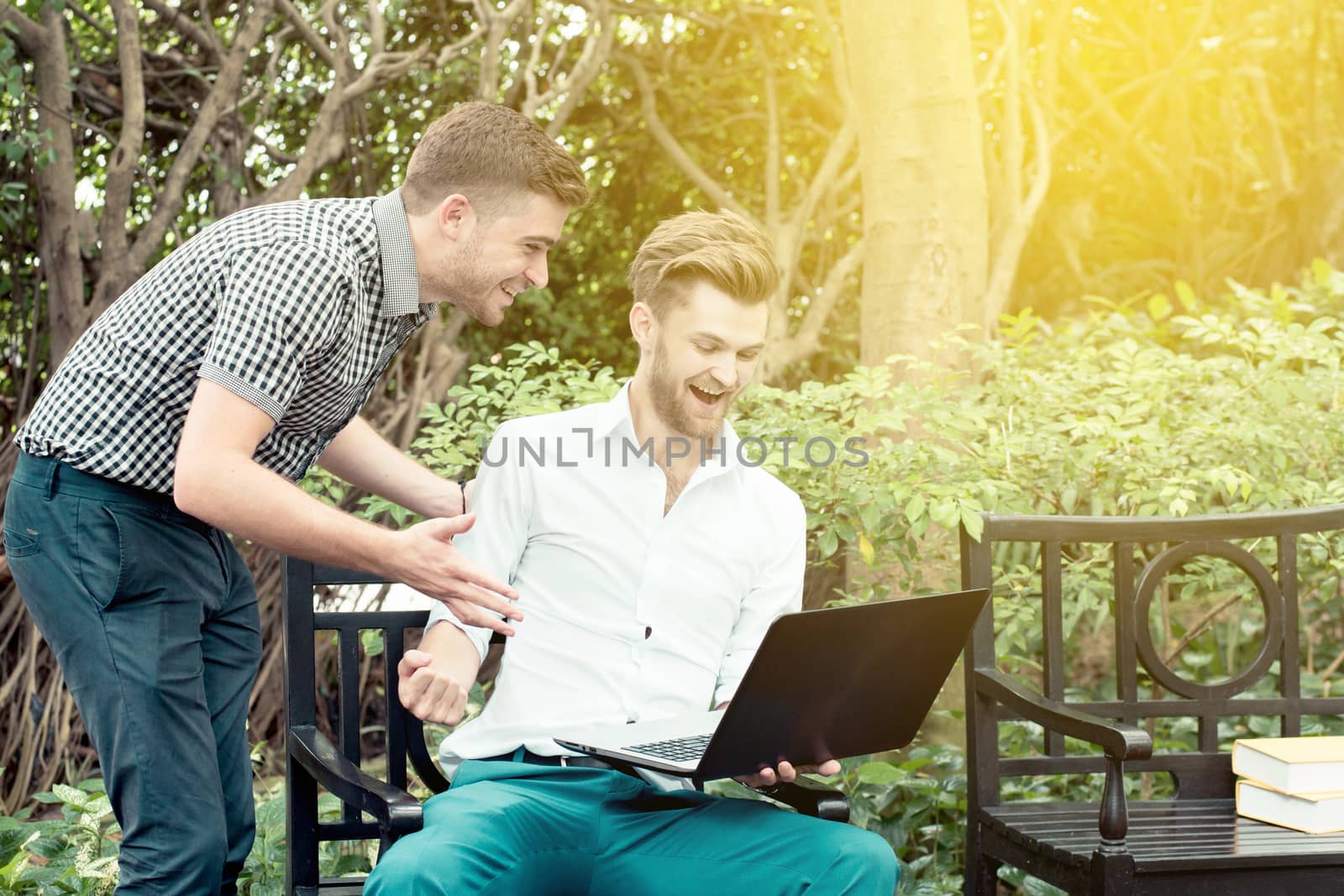 Two business people looking of the notebook computer with gasture glad success at outdoor.