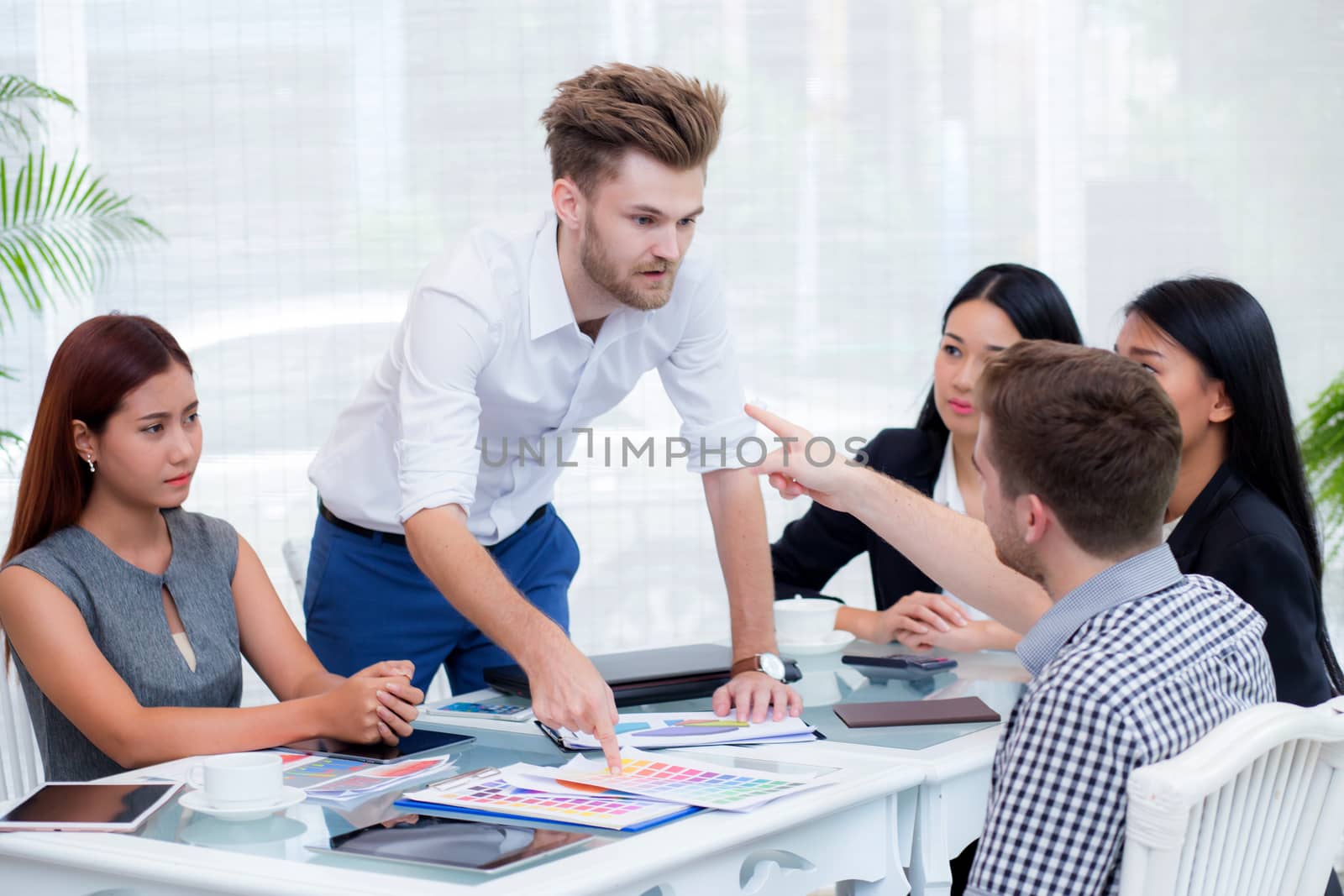 Group of businesspeople looking at businessman blaming his colleague in meeting