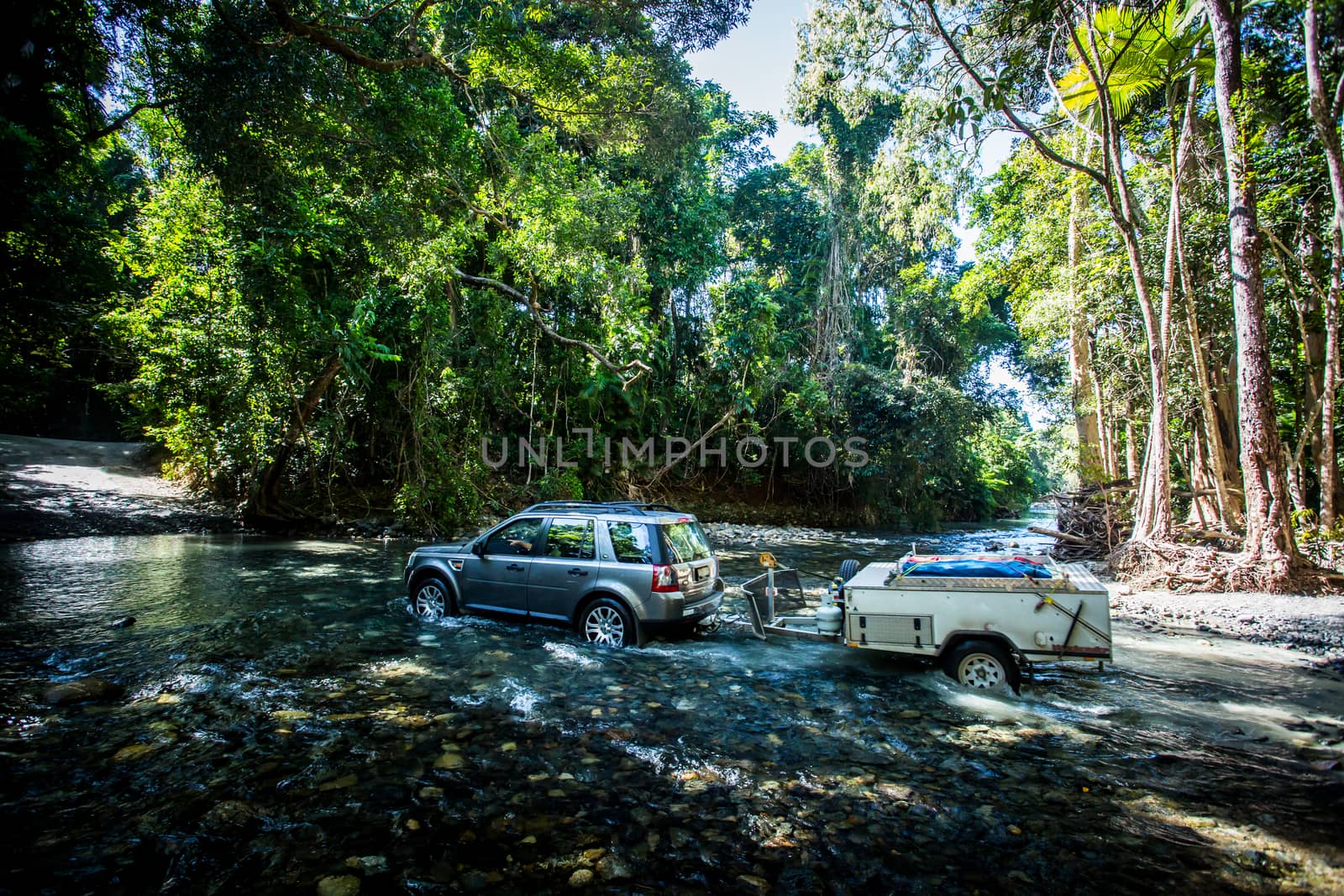 A car drives along Cape Tribulation Rd and crosses a river near Cape Tribulation in the Daintree, Queensland, Australia