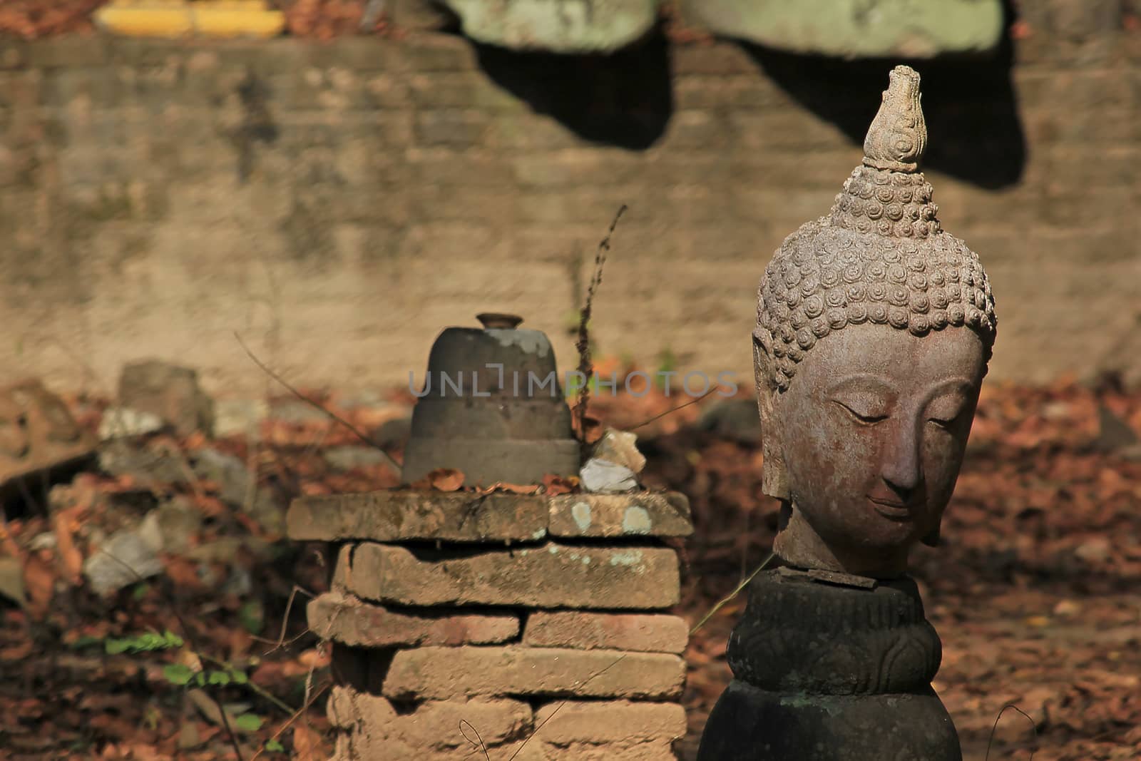 The head of an old Buddha statue, traces of erosion on the ground