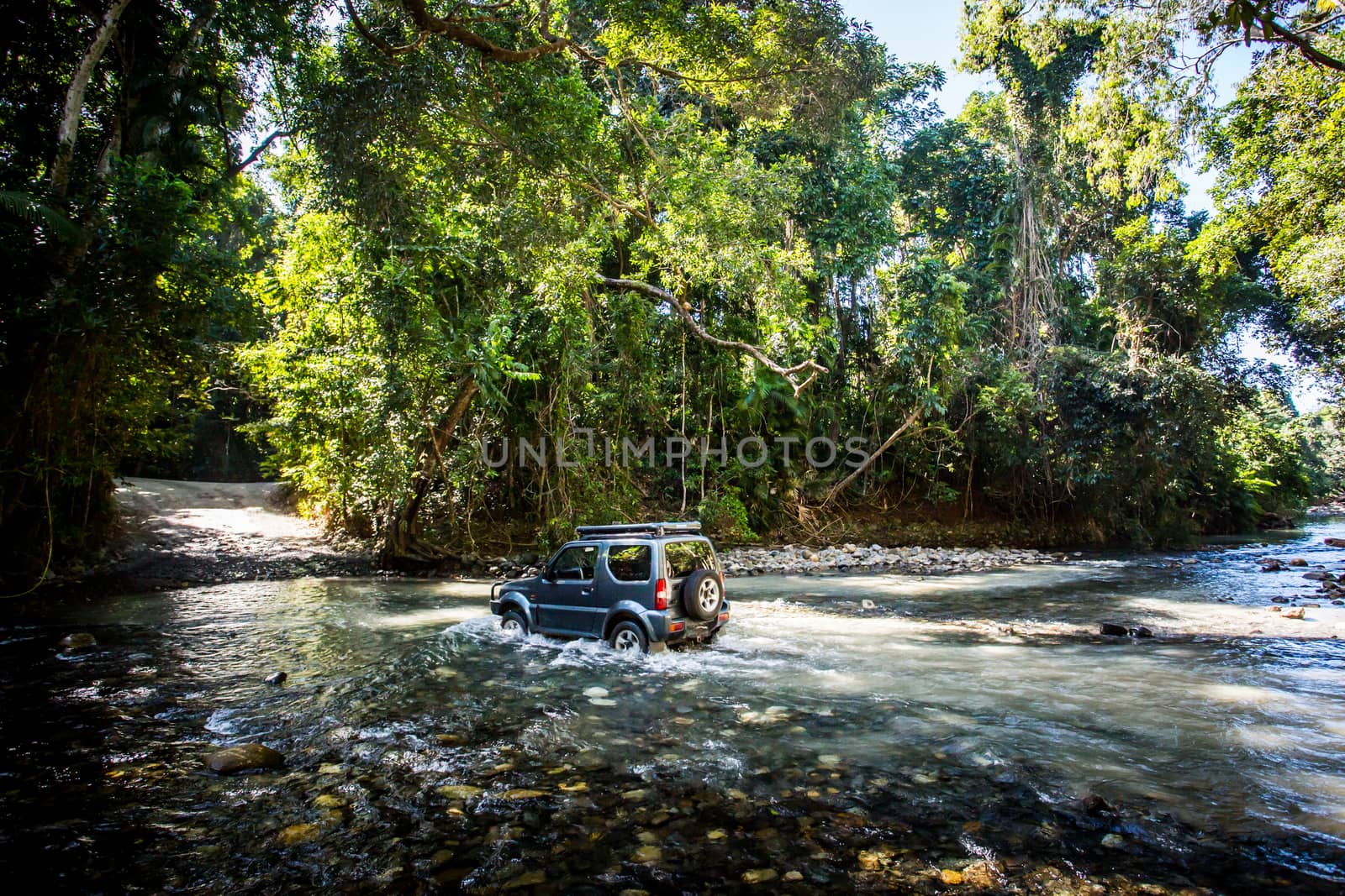 A car drives along Cape Tribulation Rd and crosses a river near Cape Tribulation in the Daintree, Queensland, Australia