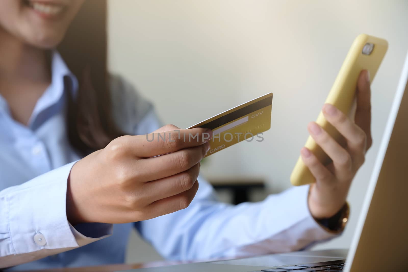 Close up hand of woman holding credit card and using laptop computer at home. Online shopping concept by nateemee