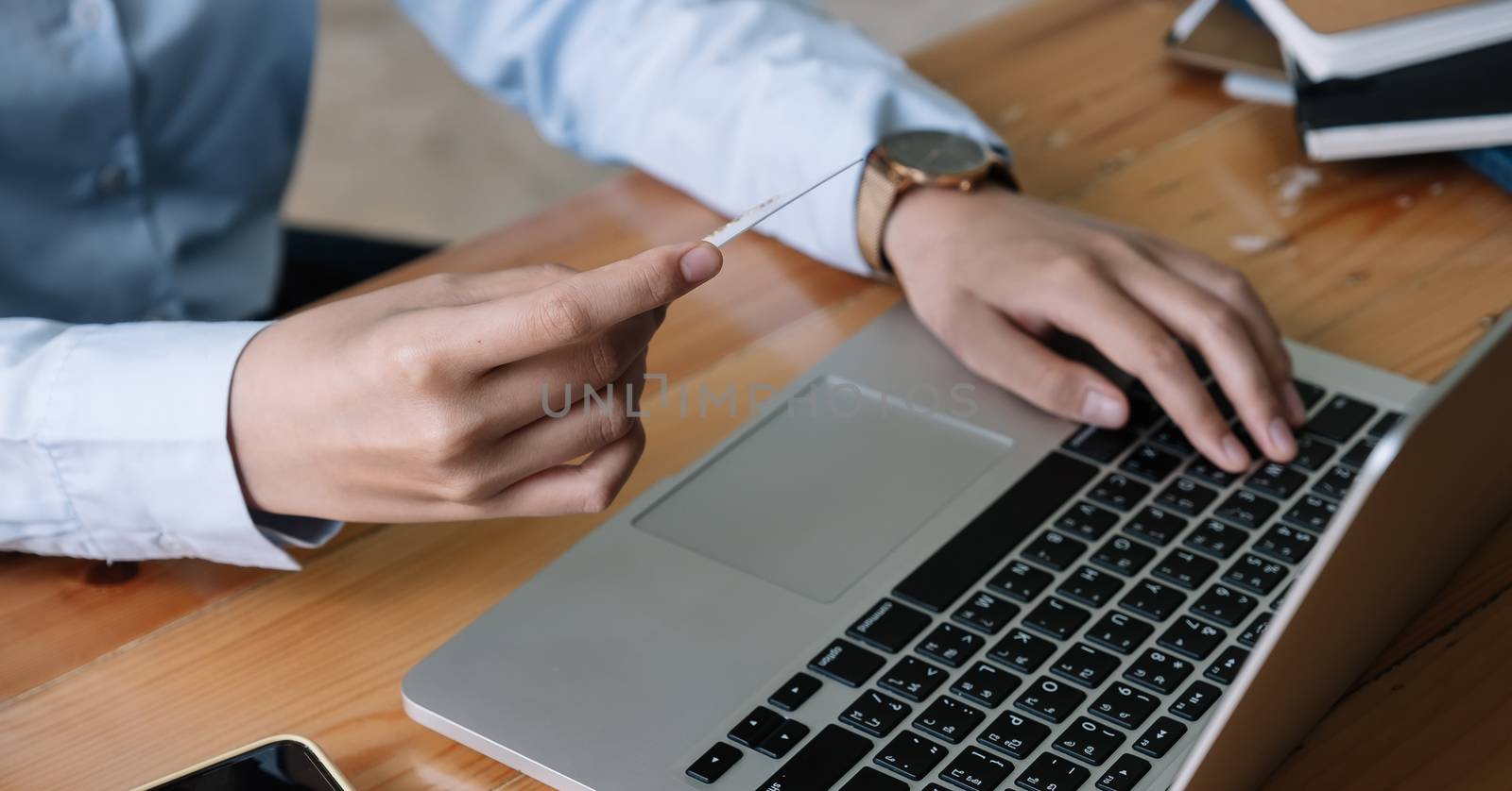 Close up hand of woman holding credit card and using laptop computer at home. Online shopping concept.