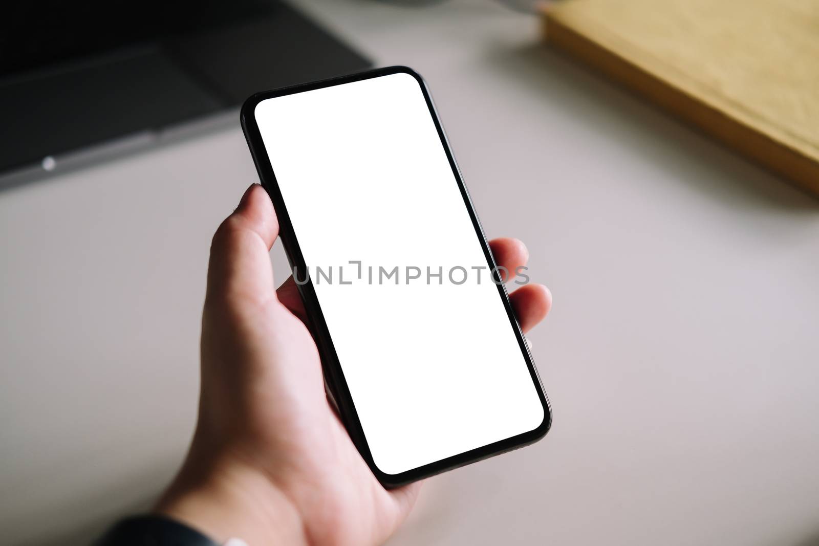 Woman using smart phone with blank screen mock up on workplace desk. by nateemee