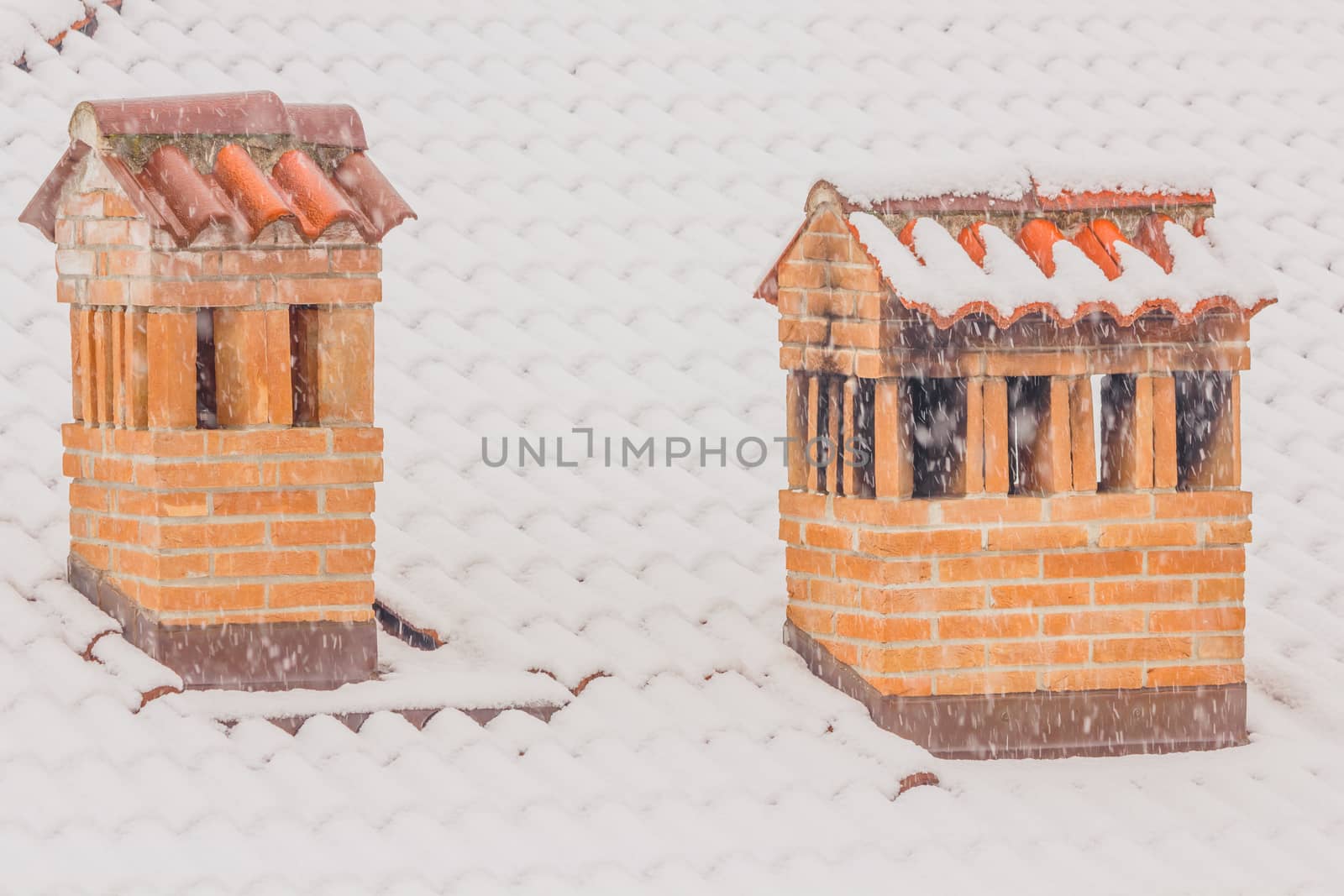 the chimneys of a house during a heavy snowfall by moorea