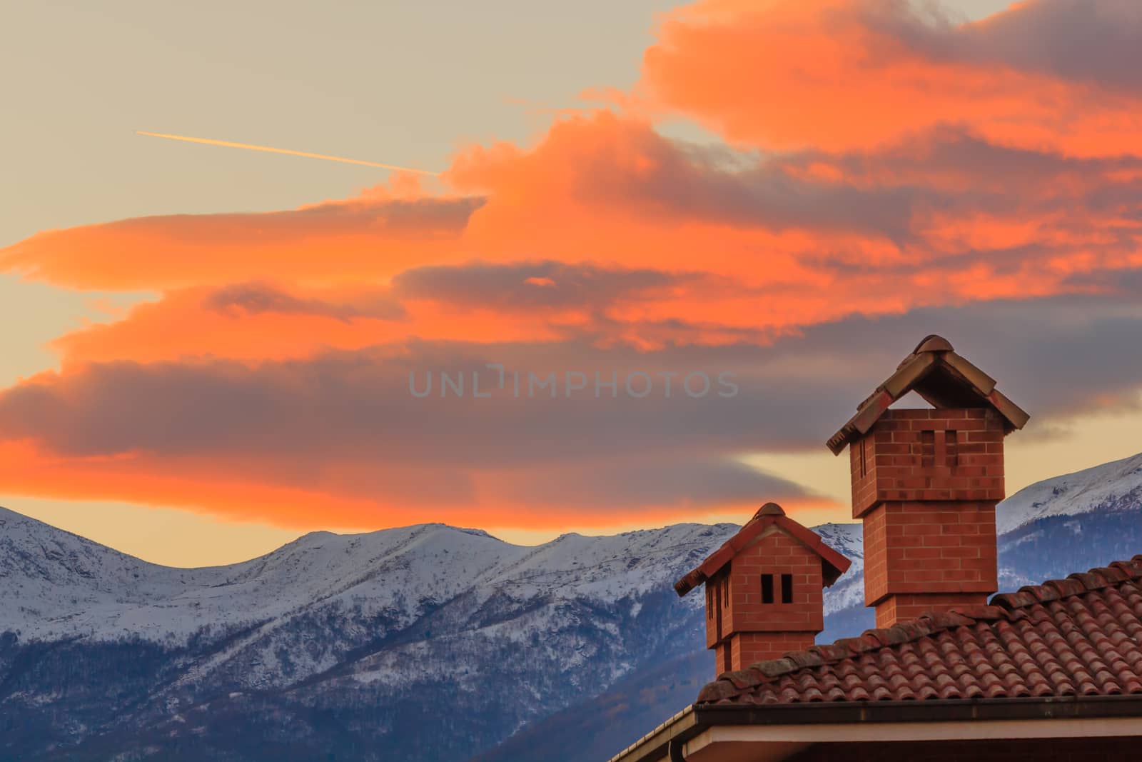 the profiles of two chimneys drawn against the background of a mountain at sunset