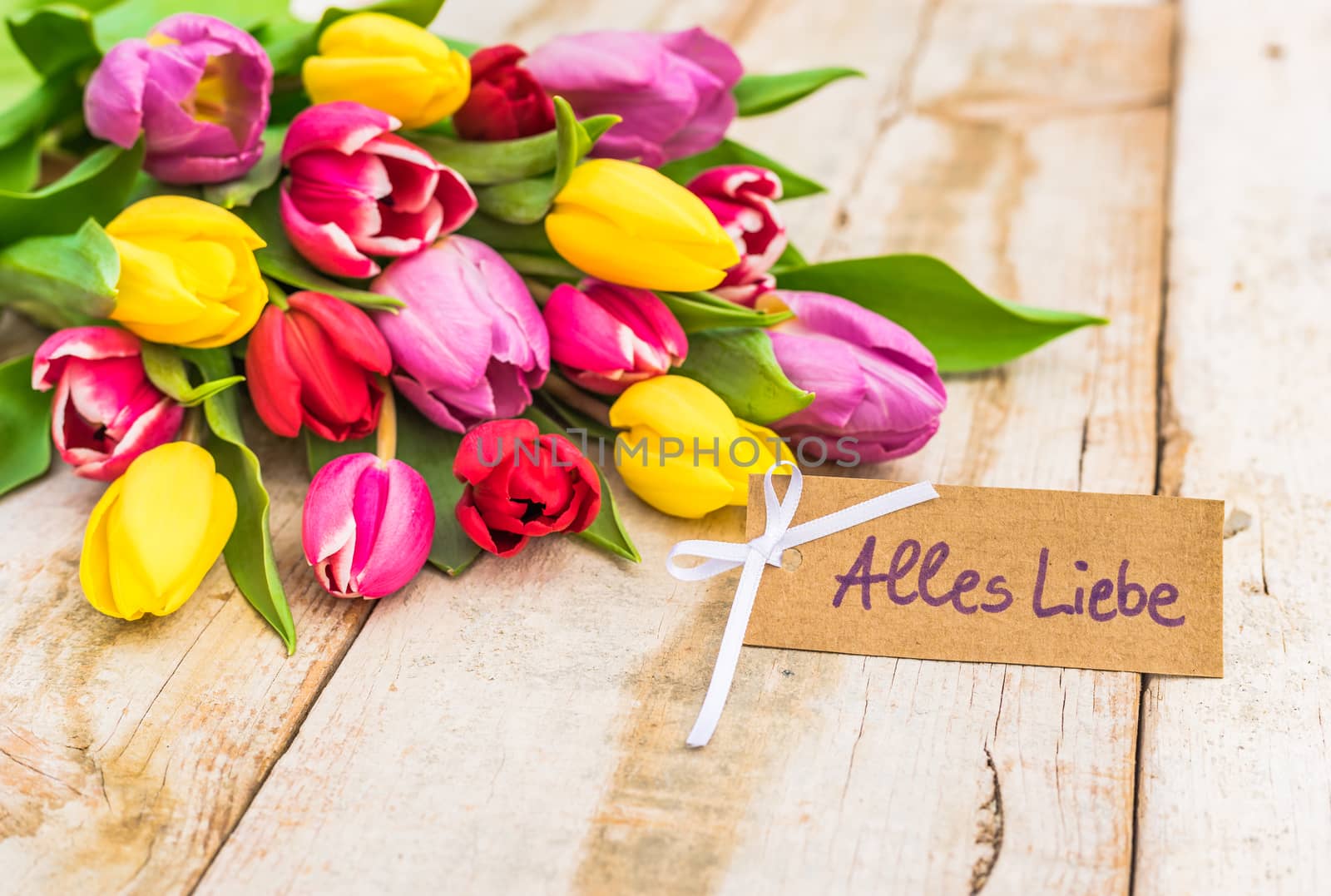 Beautiful bouquet of flowers with greeting card with german text, Alles Liebe, means love