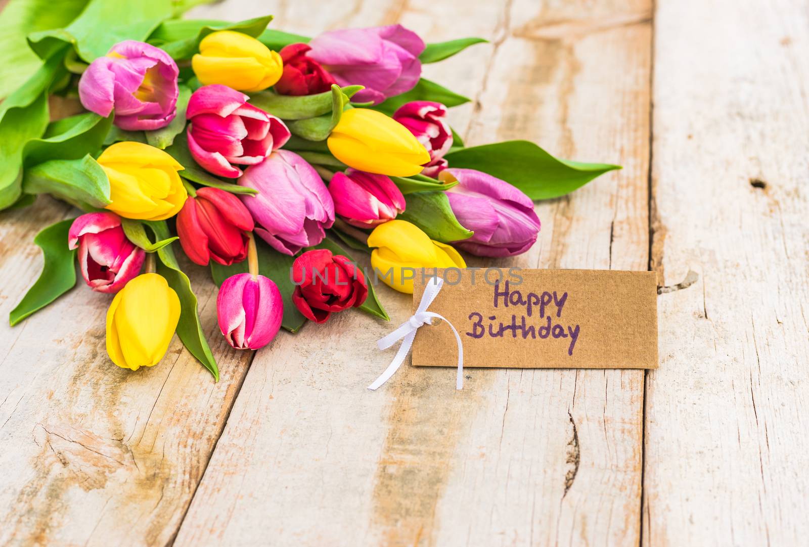 Beautiful bunch of flowers with Happy Birthday card on wooden table