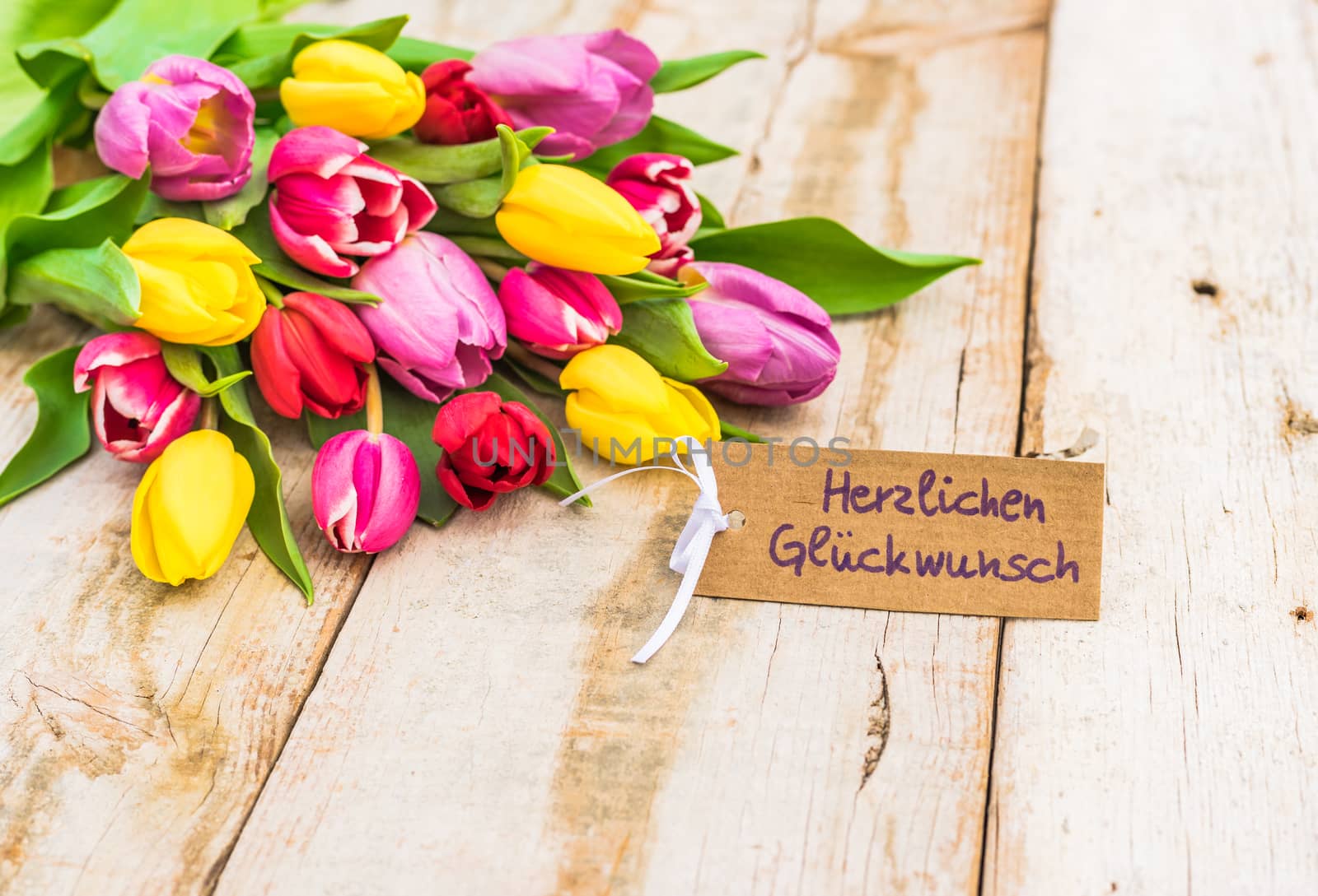 Beautiful bouquet of flowers with greeting card with german text, Herzlichen Glueckwunsch, means congratulation