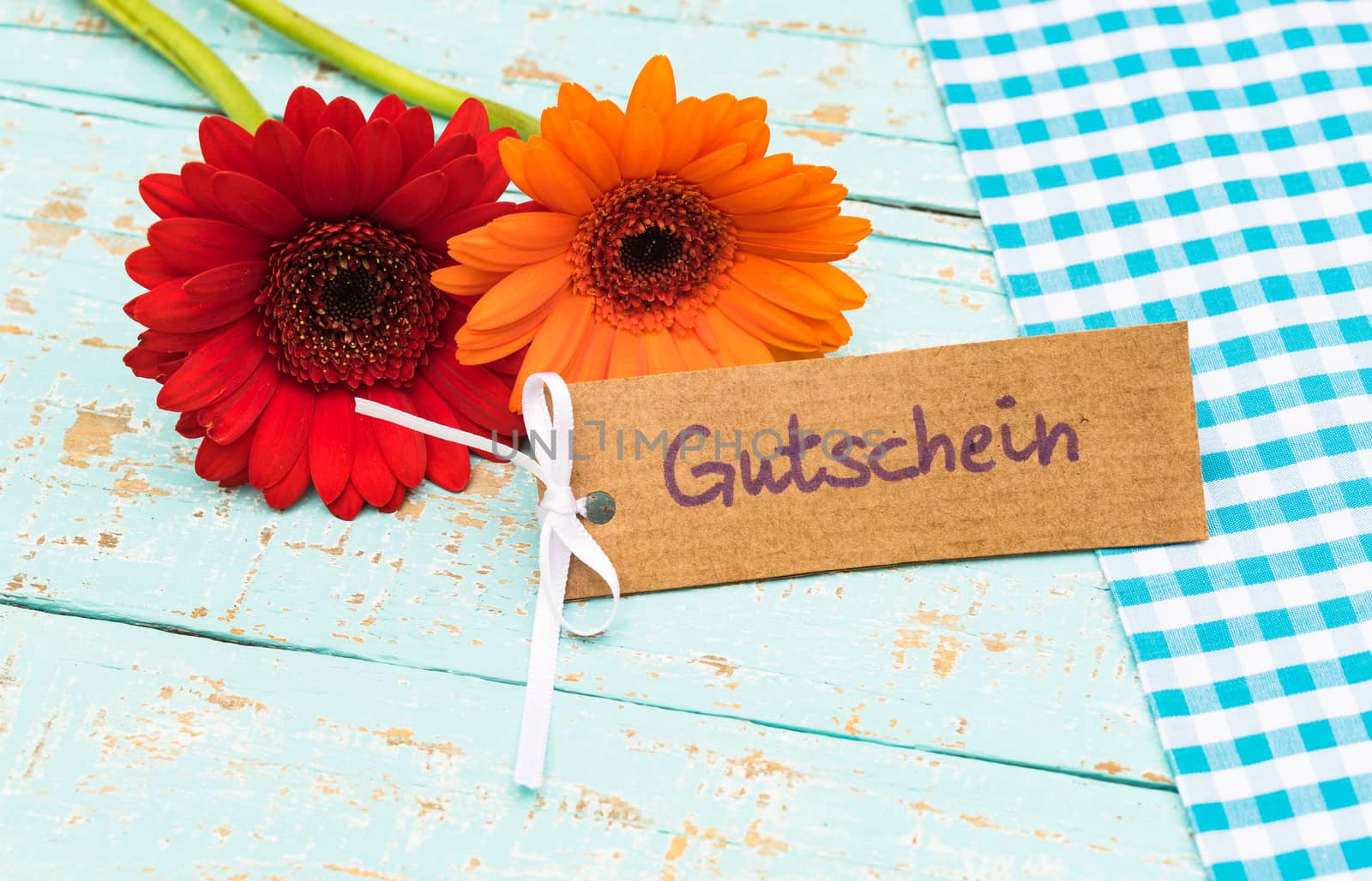 Red and orange flowers gift with label with german word, Gutschein, means voucher or coupon