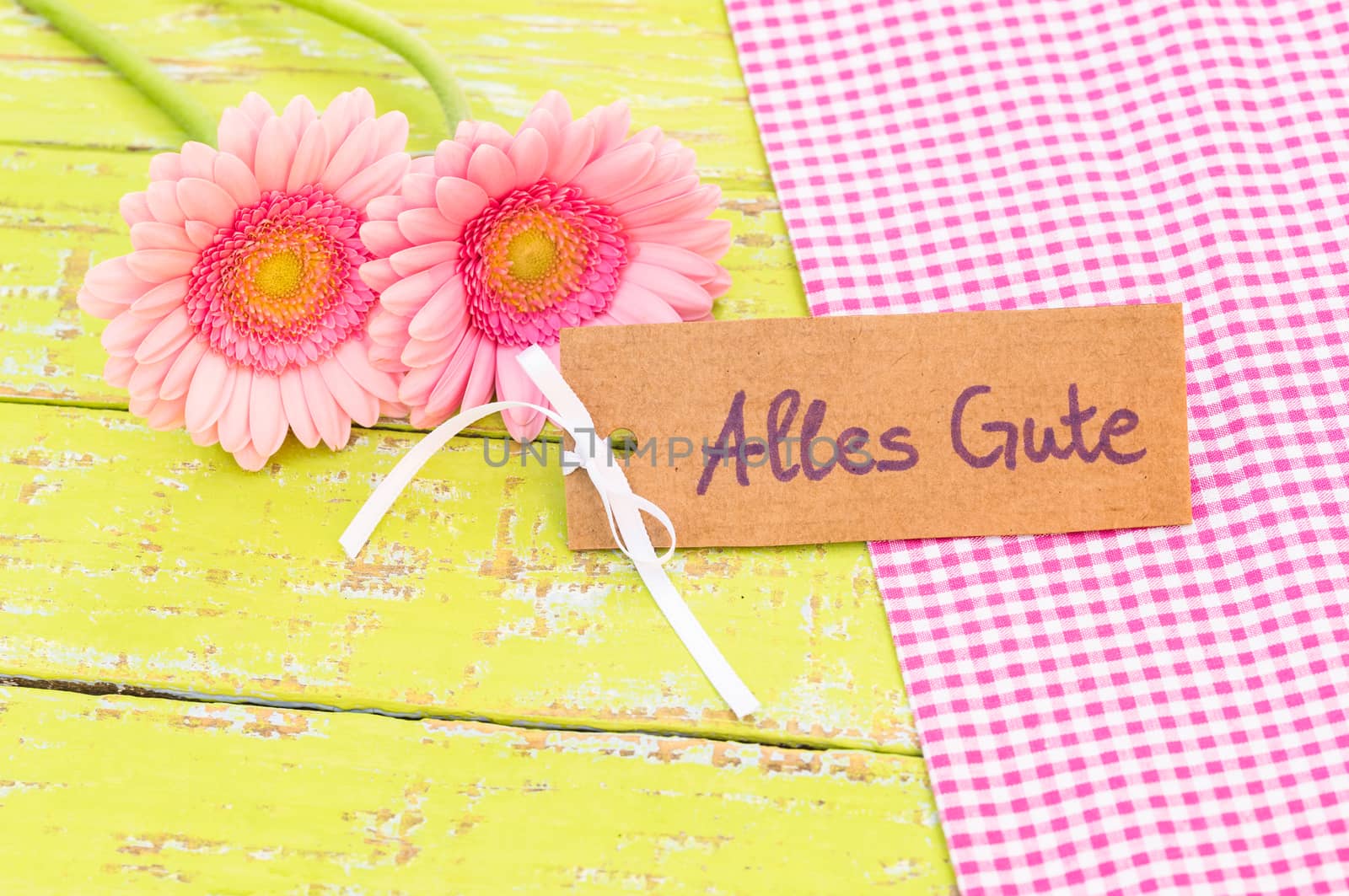 Pink gerbera flowers and card with german text, Alles Gute, means best wishes
