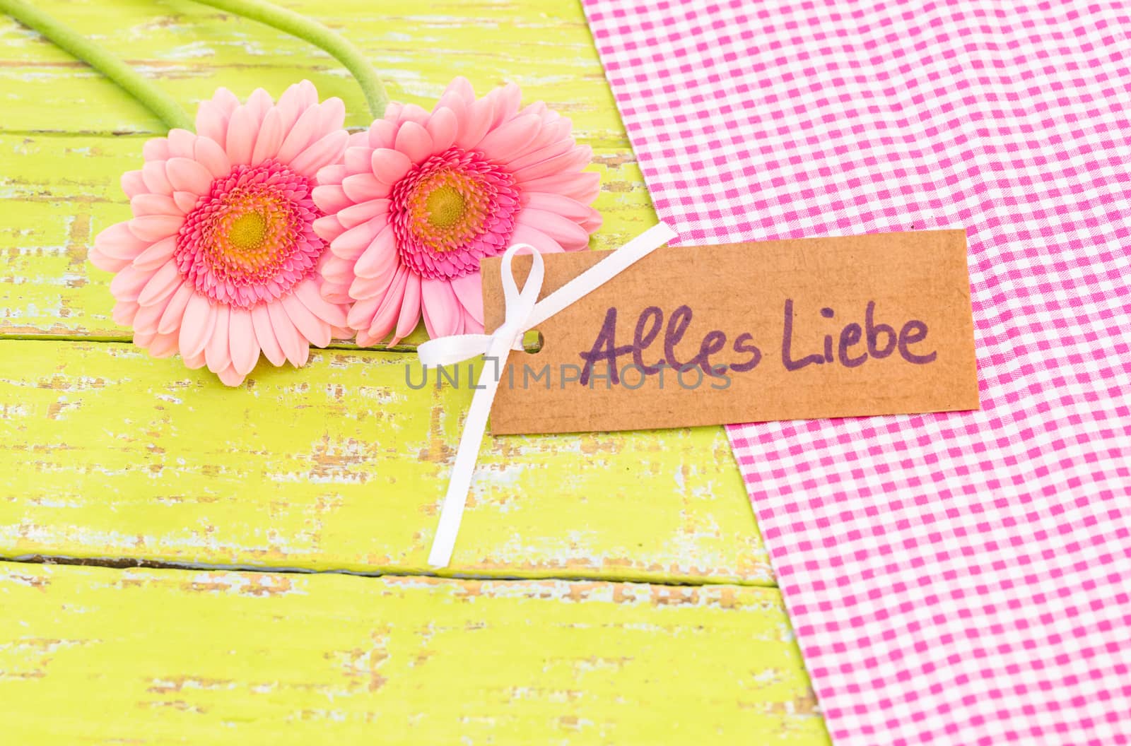 Pink gerbera flowers with card with german text, Alles Liebe, means love