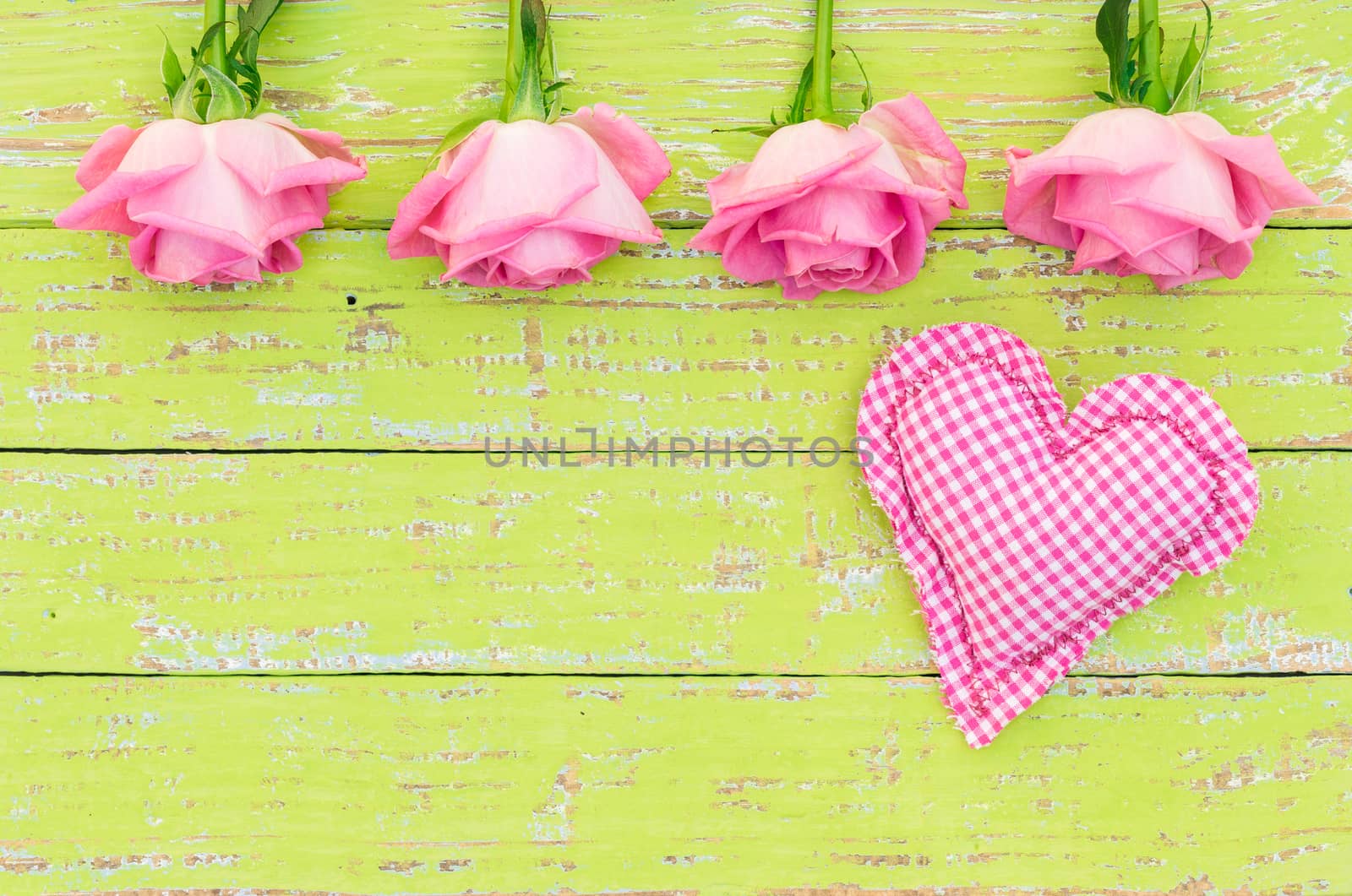 Pink roses with romantic heart on green wooden background with copy space