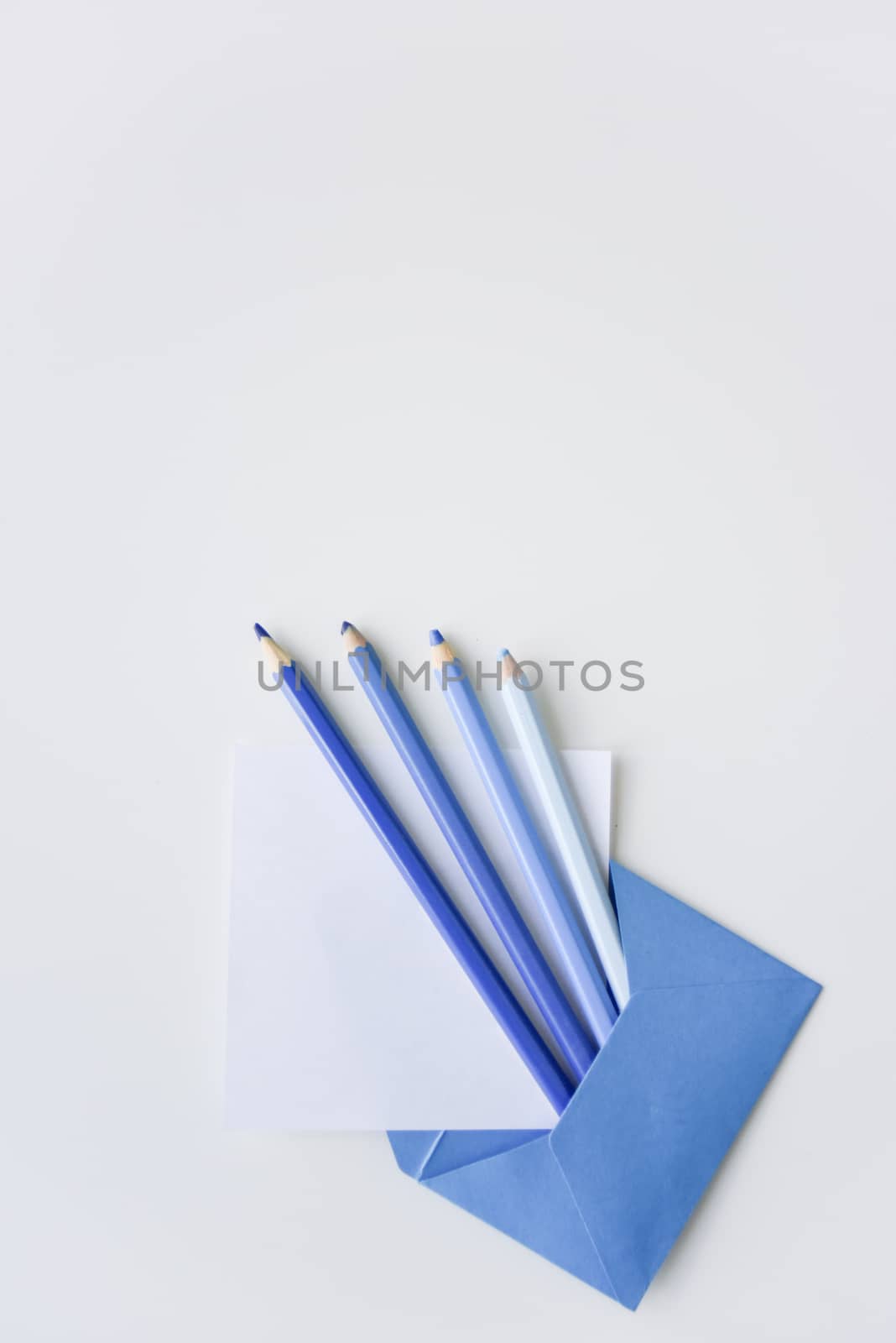 selective focus, four blue pencils and white paper sheet out of the blue envelope