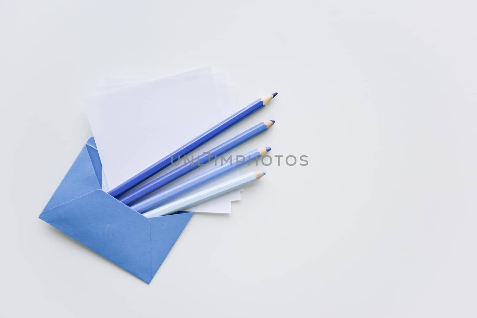 fselective focus, our blue pencils and white papers out of the blue envelope with copy space on top