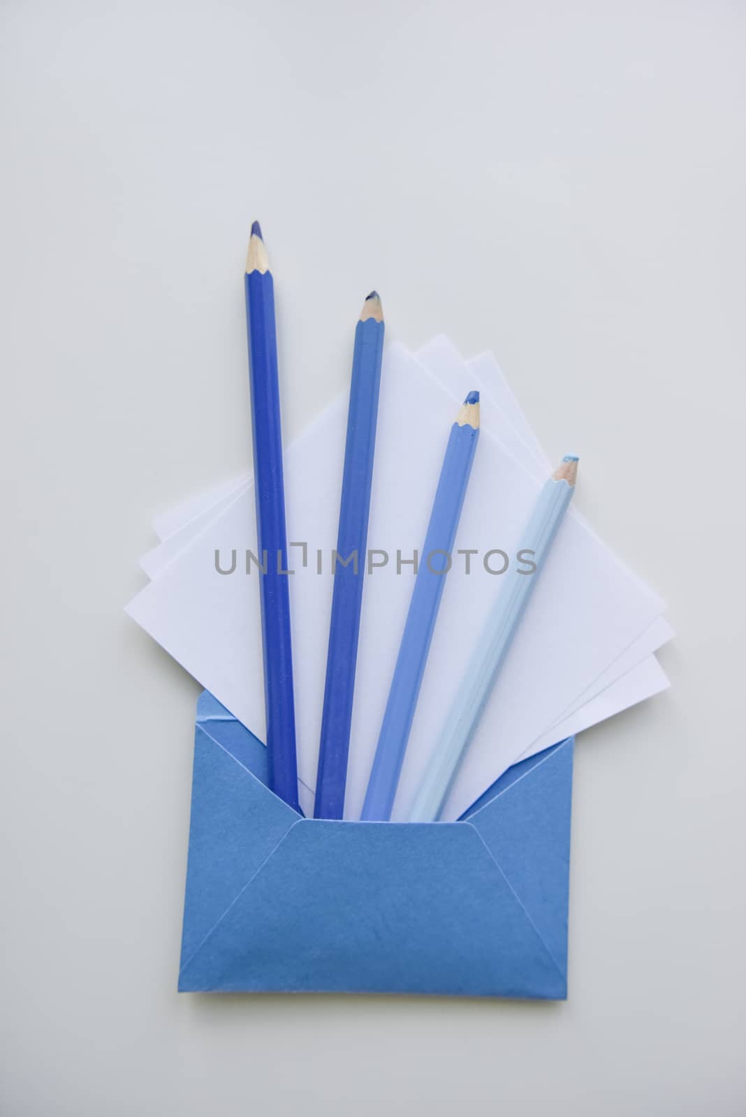 selective focus, four blue pencils and white papers out of the blue envelope