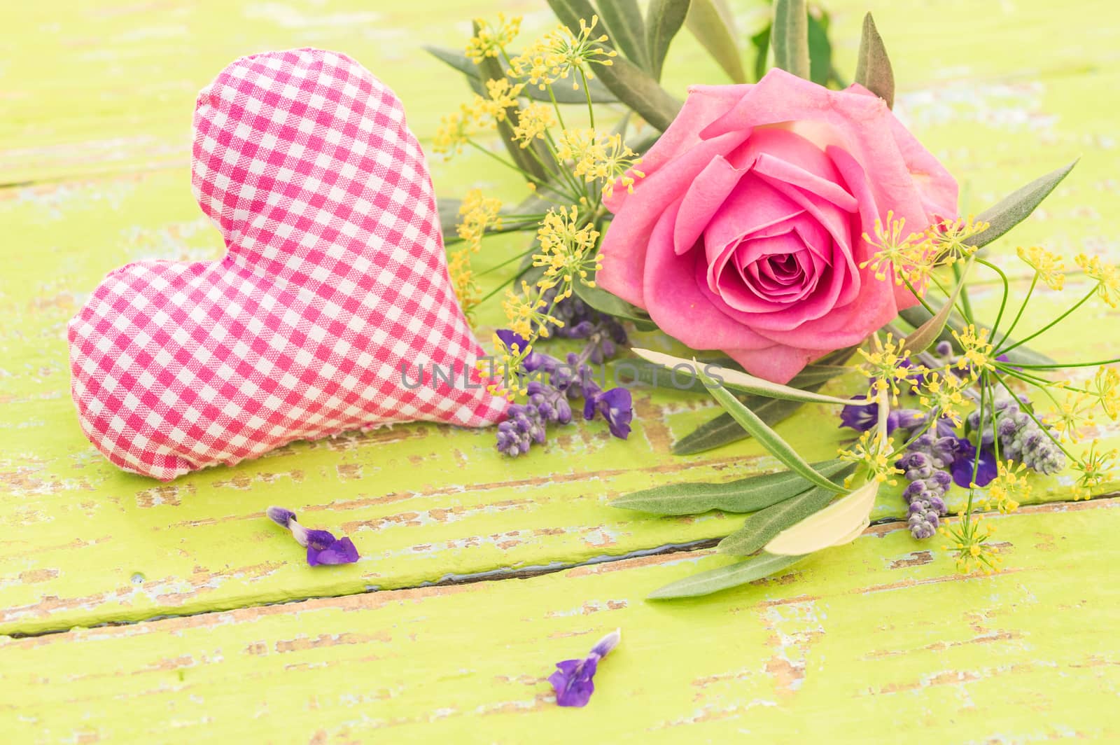 Love background with heart and bunch of flowers with pink rose on yellow wood, closeup