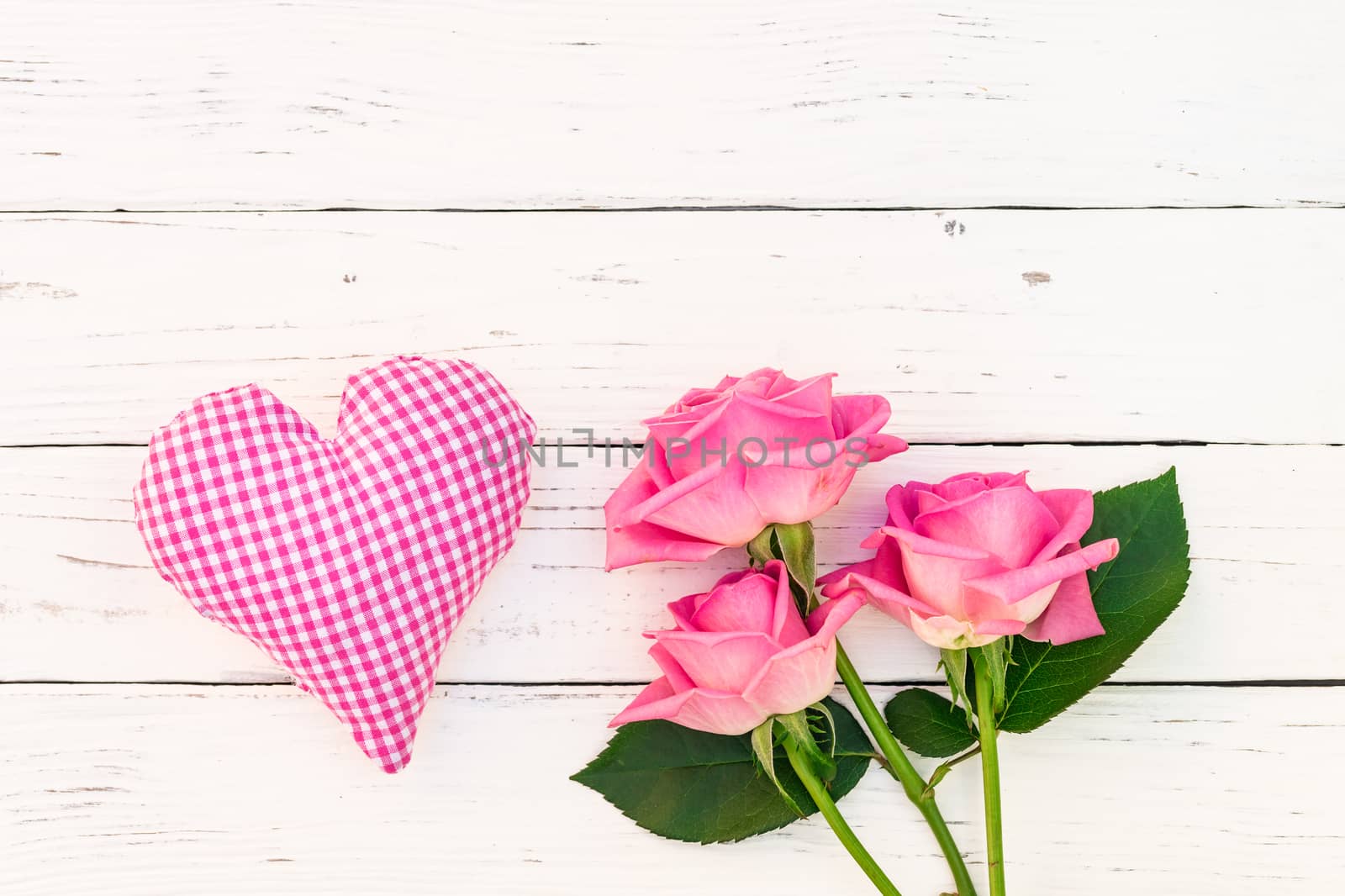 Pink heart with bunch of roses on white wood with copy space 