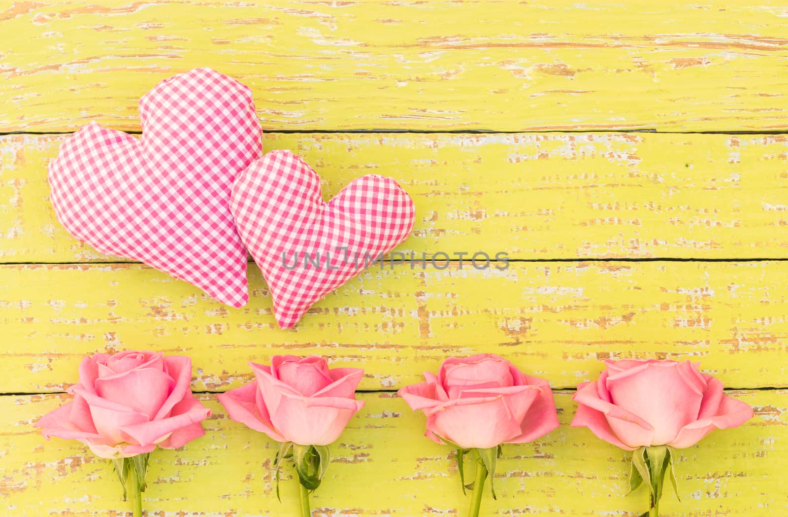 Pink roses with two love hearts on yellow wood, background for Valentines day