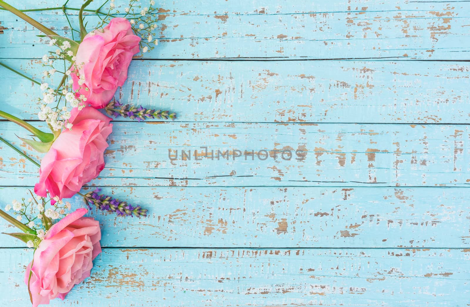Beautiful pastel colored flowers of pink roses, gypsophila and lavender on turquoise wooden background with copy space