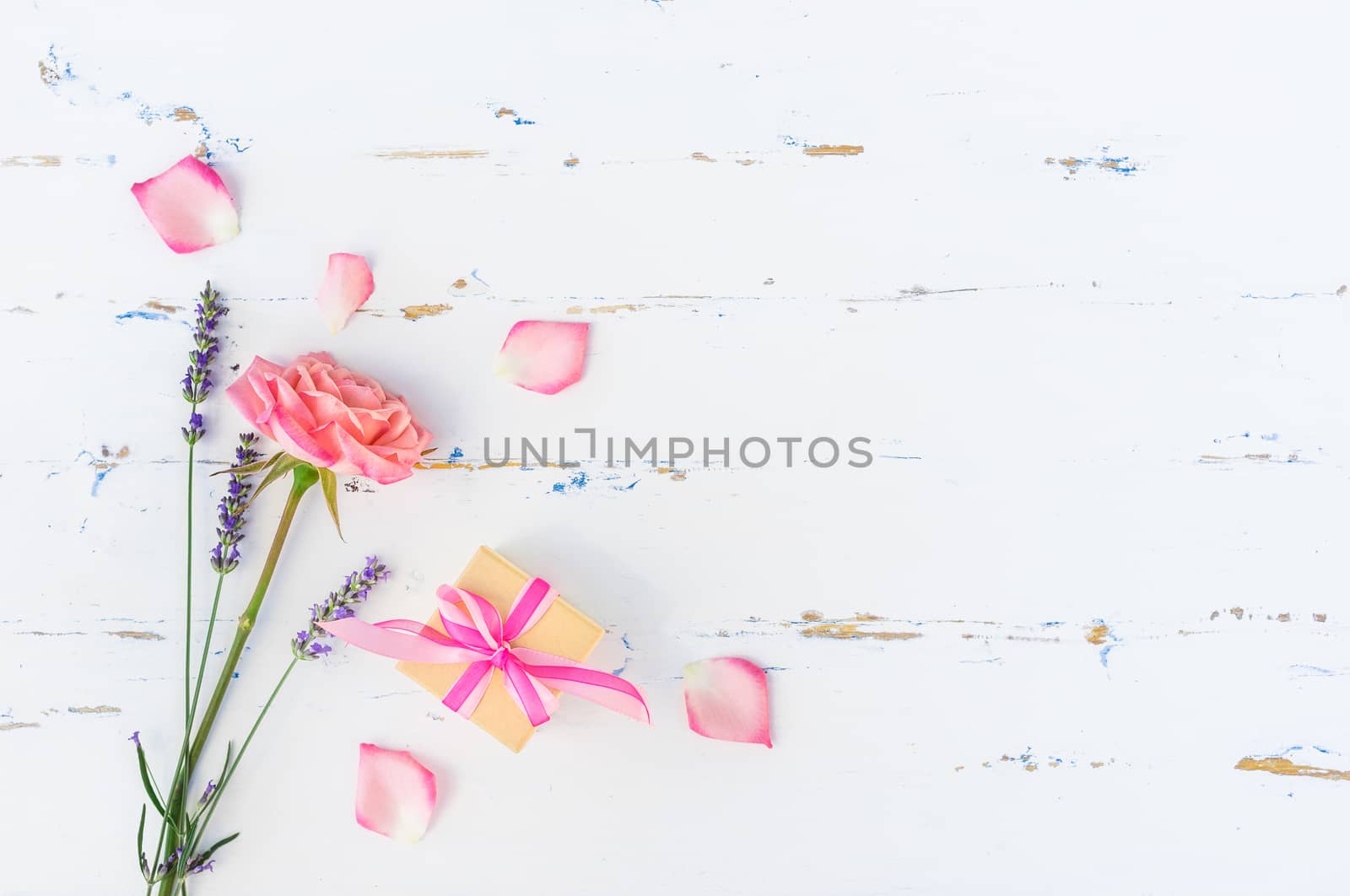 Romantic bunch of flowers with rose and lavender and small present on white wooden background with copy space