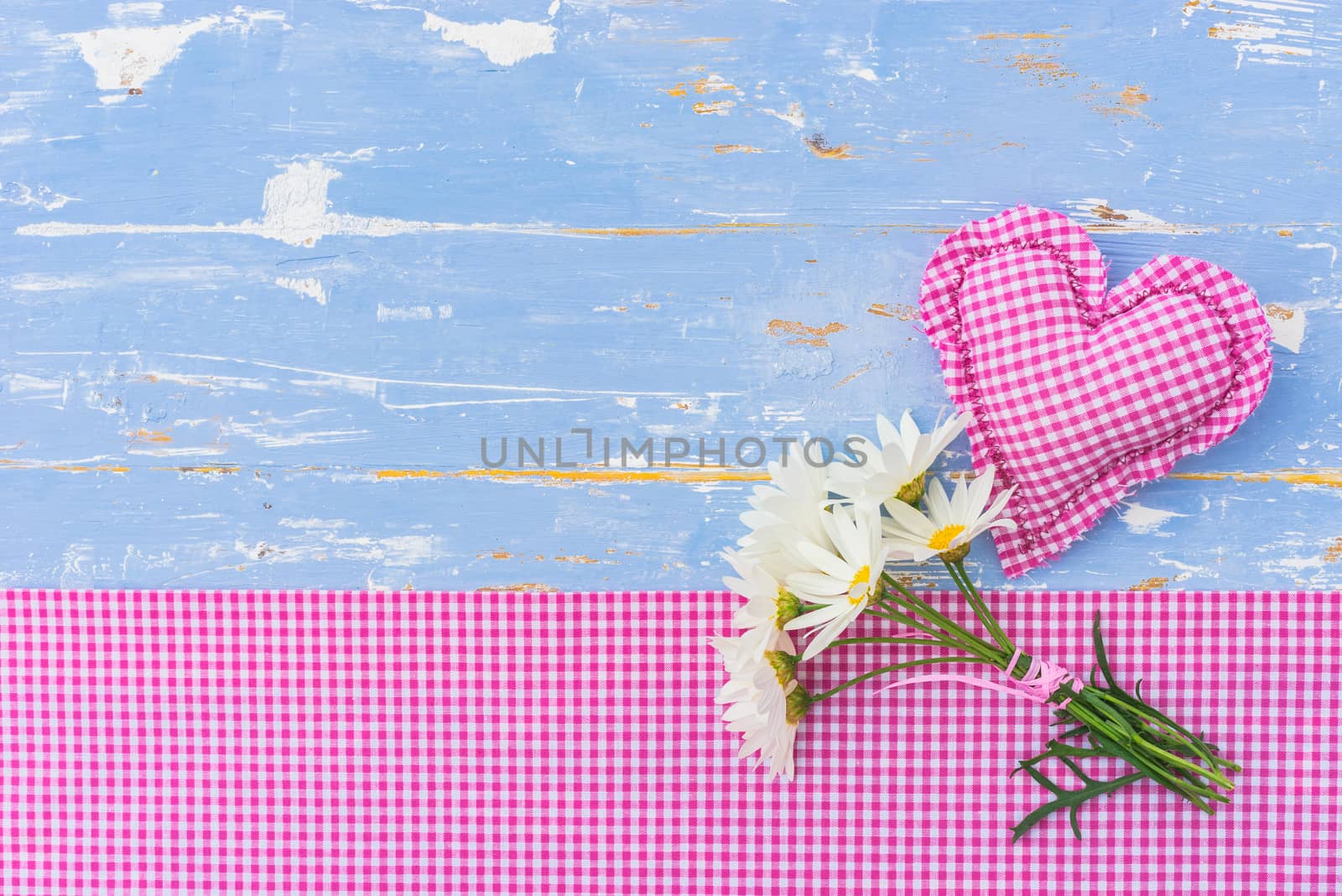 Romantic background with pink heart and daisy flowers on blue wood with copy space
