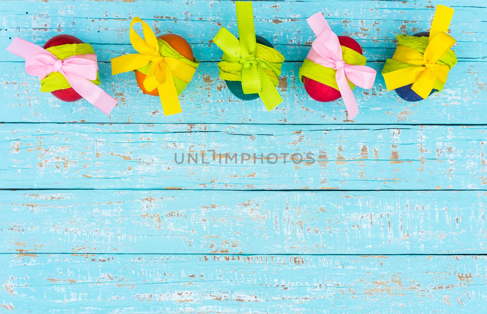 Multicolored easter eggs with ribbon bow on blue wooden background