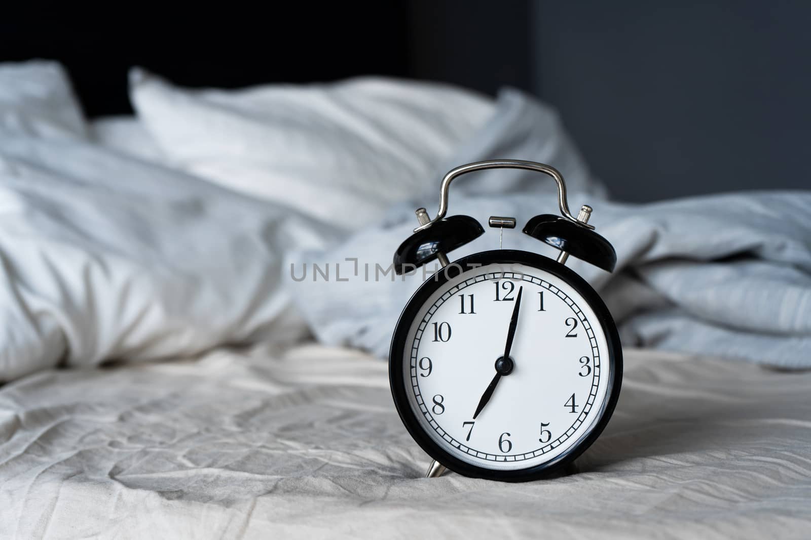 Stylish alarm clock with a bell. The hands show 7 hours. Wake up time.