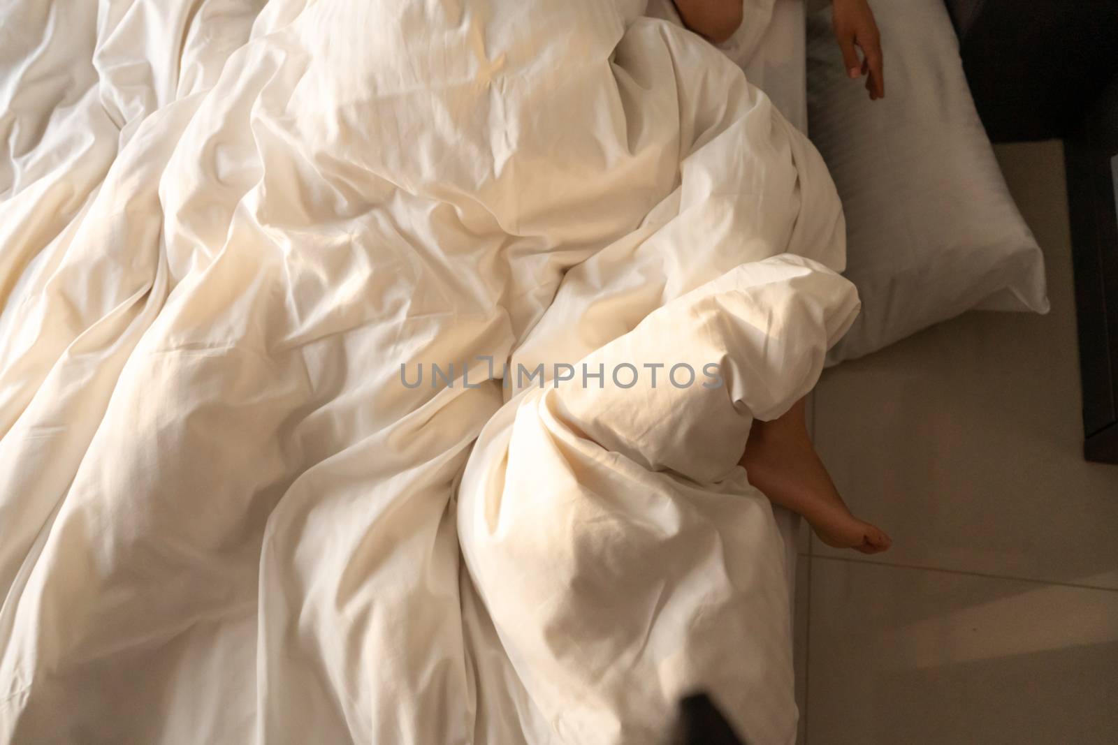 The foot of a sleeping girl in the morning hangs down the bed. Spy photo. Deep sleep