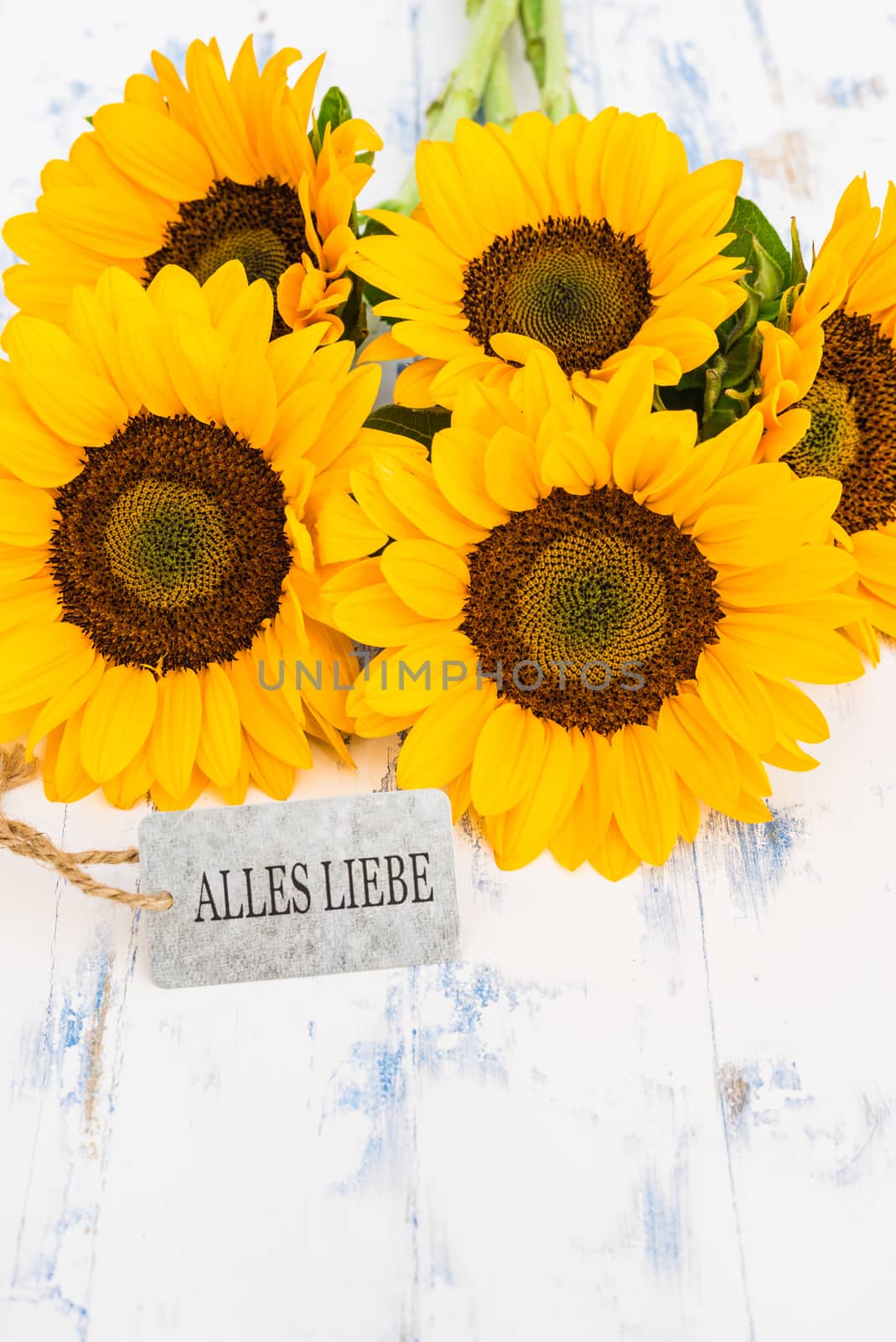 Bouquet of yellow sunflowers and greeting card with german text, Alles Liebe, means best wishes