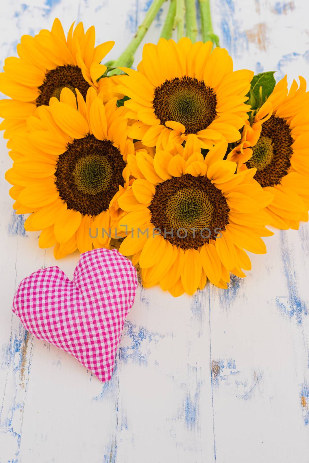 Bouquet of sunflowers with pink heart on wooden background with copy space