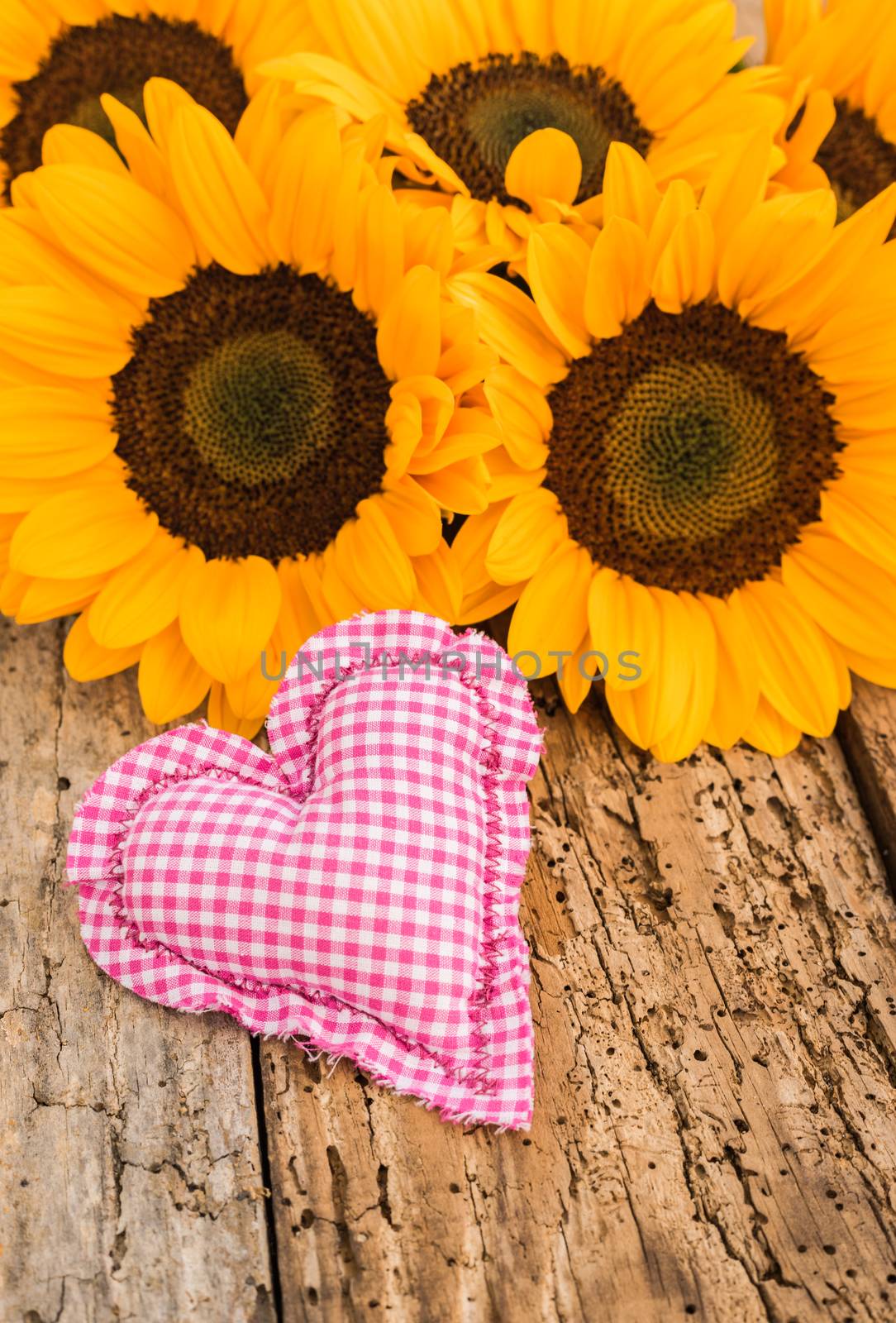 Romantic heart and beautiful yellow sunflowers arrangement on rustic wooden background