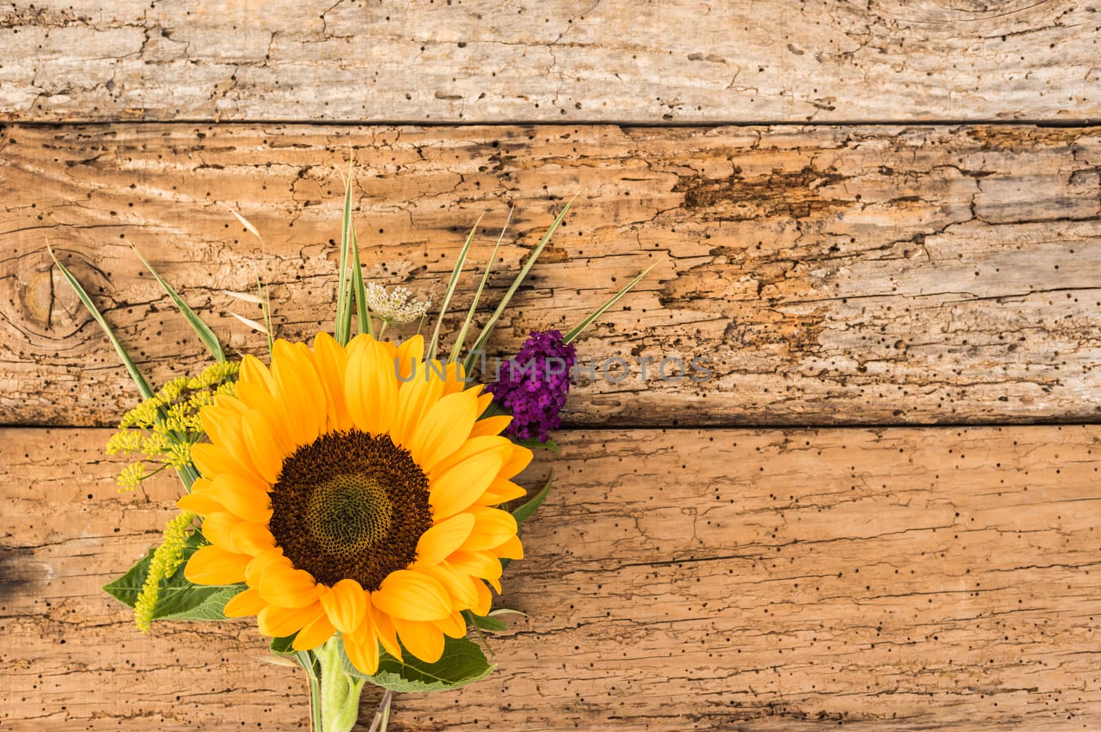 Rustic bouquet of flowers with sunflower on old wooden background with copy space