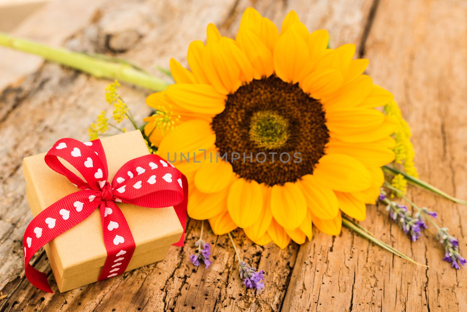 Bunch of flowers with yellow sunflower and gift box on rustic wood