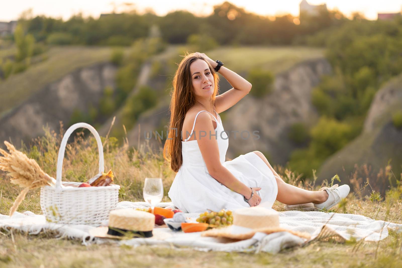 Gorgeous young brunette girl in a white sundress having a picnic in a picturesque place. Romantic picnic by Try_my_best