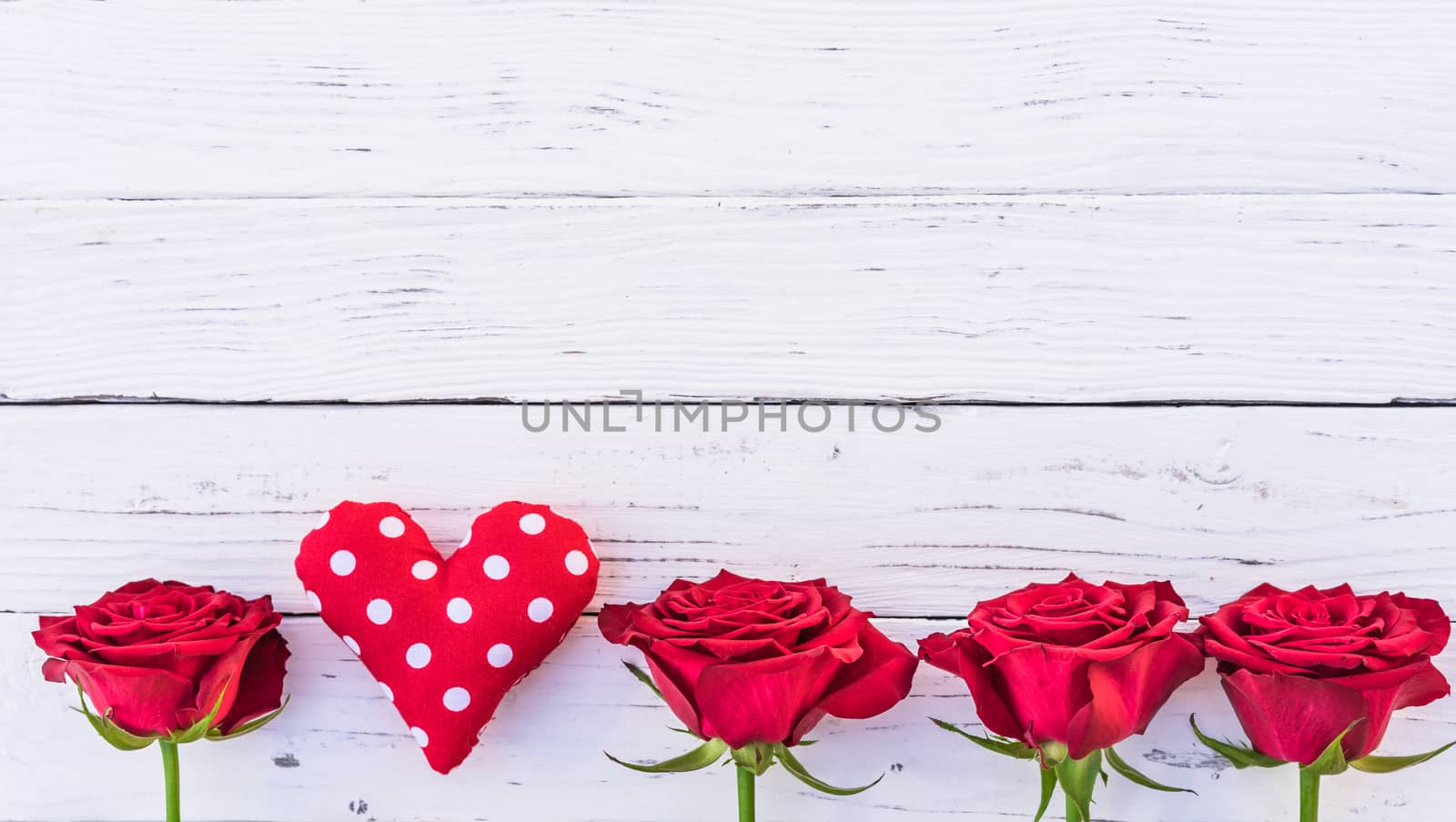 Romantic red roses border with love heart on white wooden background