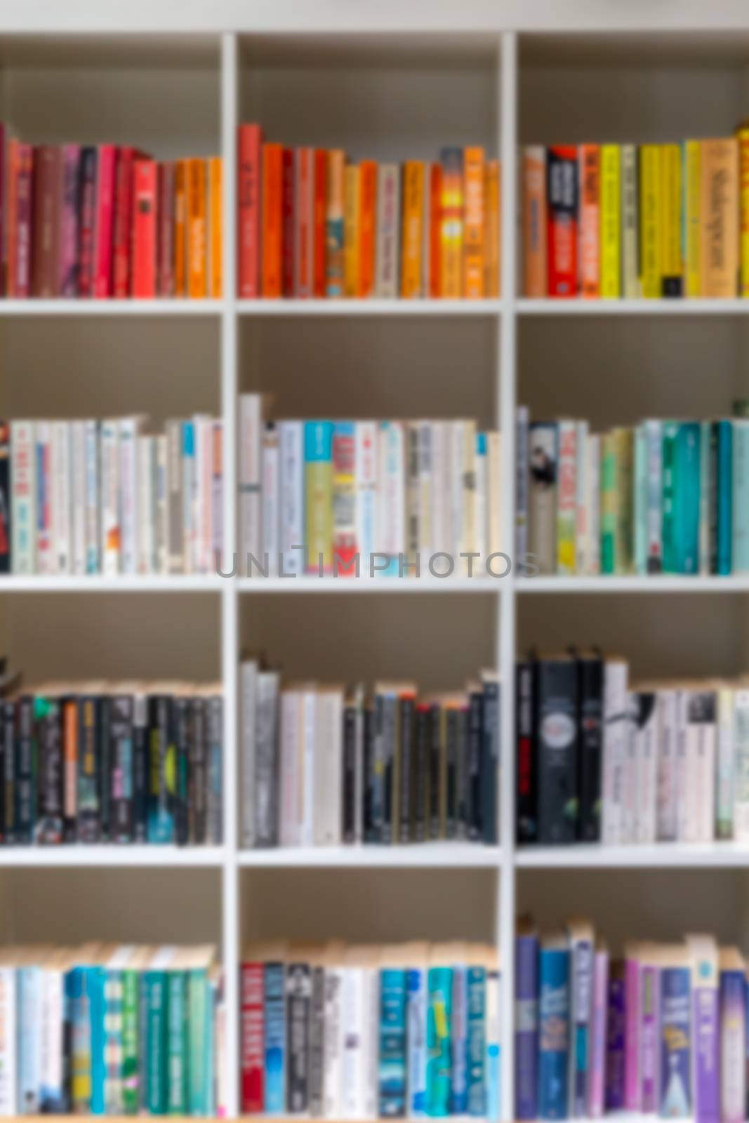 Blurred image of white wooden bookcase filled with books by magicbones