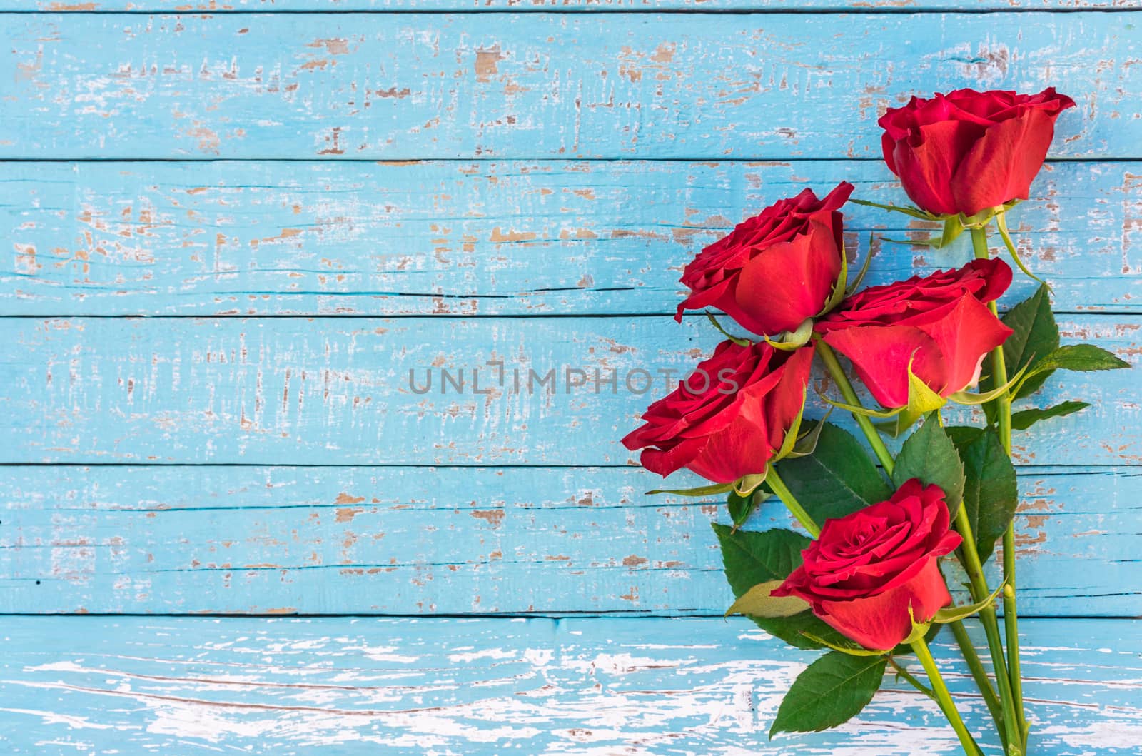 Romantic bunch of red rose flowers on blue wood background with copy space