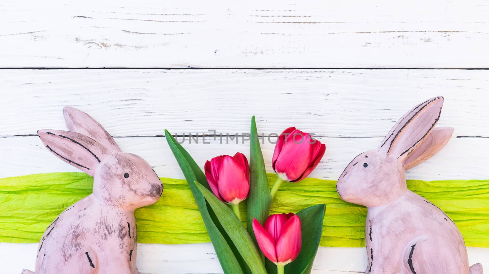 Happy easter background with rabbits and bunch of tulip flowers on white wood