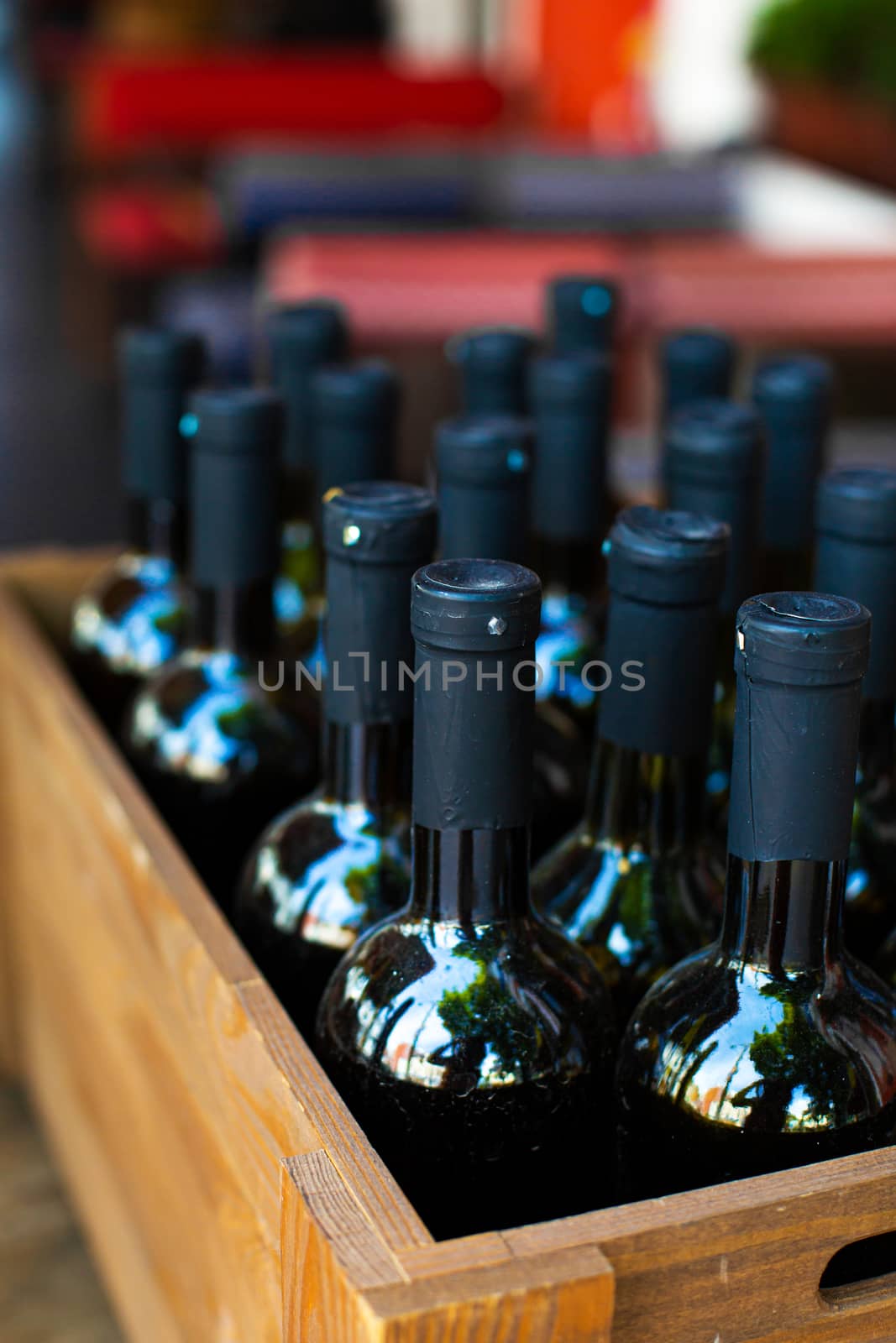 A wooden box filled with bottles of wine. Bank party celebration in an open-air restaurant.