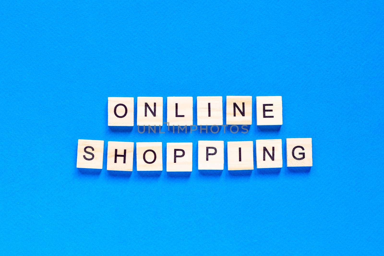 Online Shopping inscription in wooden letters on a blue background. The concept of business of delivery of online purchases. by Pirlik