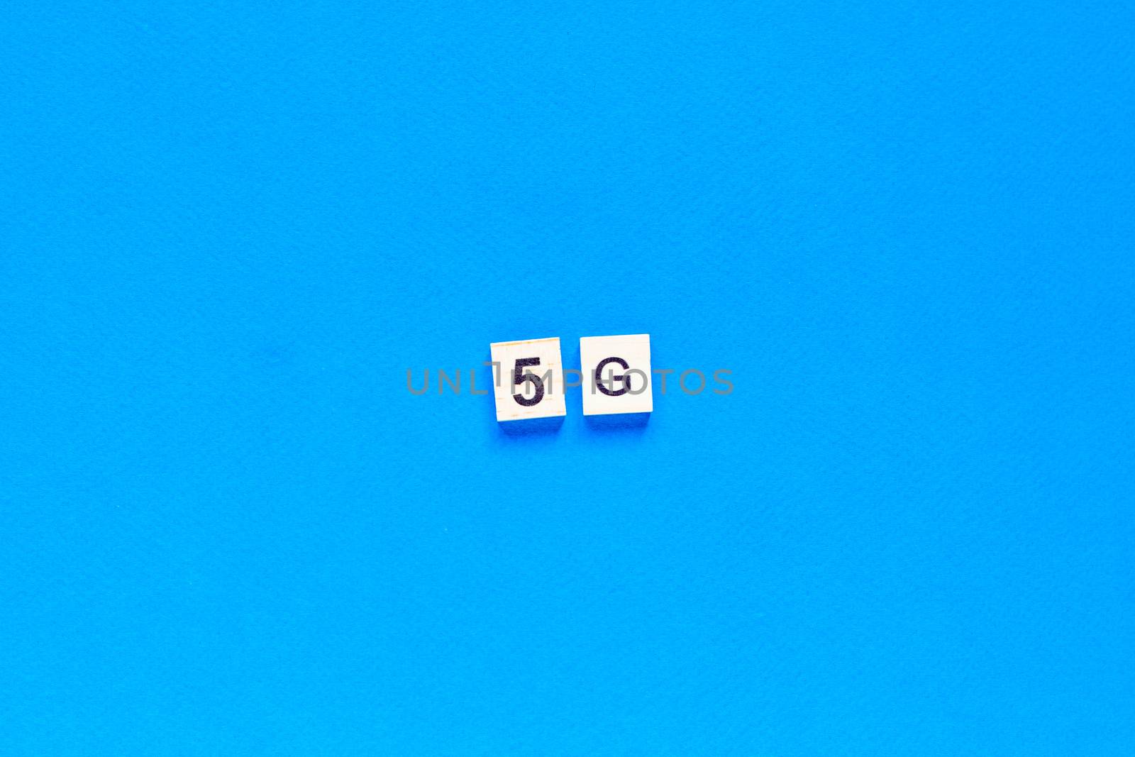 5 G. Five G's, written in wooden letters on a blue background. top view. Flat layout. Wireless network. New technology. by Pirlik
